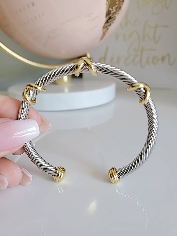 Three X Cable Cuff Bracelet featuring 18K gold filled details and stainless steel material, showcasing a unique three X pattern.