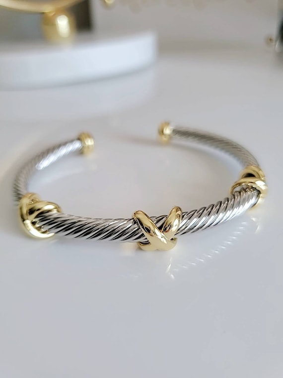 Three X Cable Cuff Bracelet featuring 18K gold filled details and stainless steel material, showcasing a unique three X pattern.