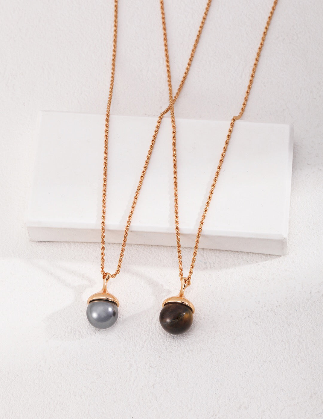 A beautiful Tiger Eye's Ball Necklace featuring gray shell beads and a tiger eye stone, elegantly designed with gold vermeil accents.