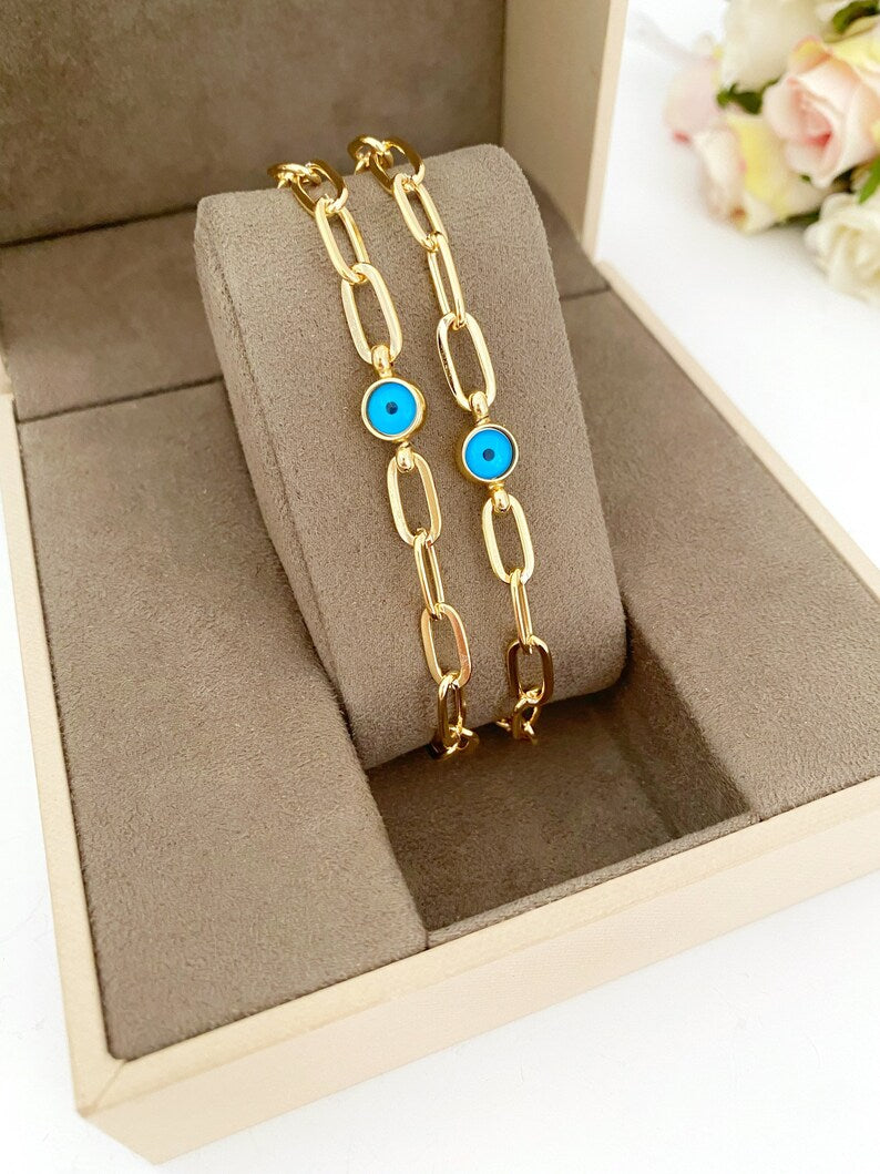 A delicate Tiny Evil Eye Bracelet featuring a gold link chain and a blue evil eye charm, showcasing its handmade craftsmanship.