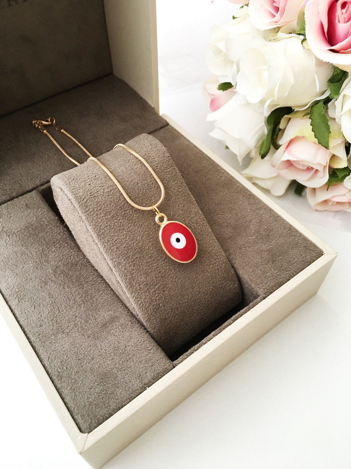 A delicate Tiny Evil Eye Necklace featuring blue and red oval brass beads on a 22K gold plated chain, symbolizing protection and good fortune.