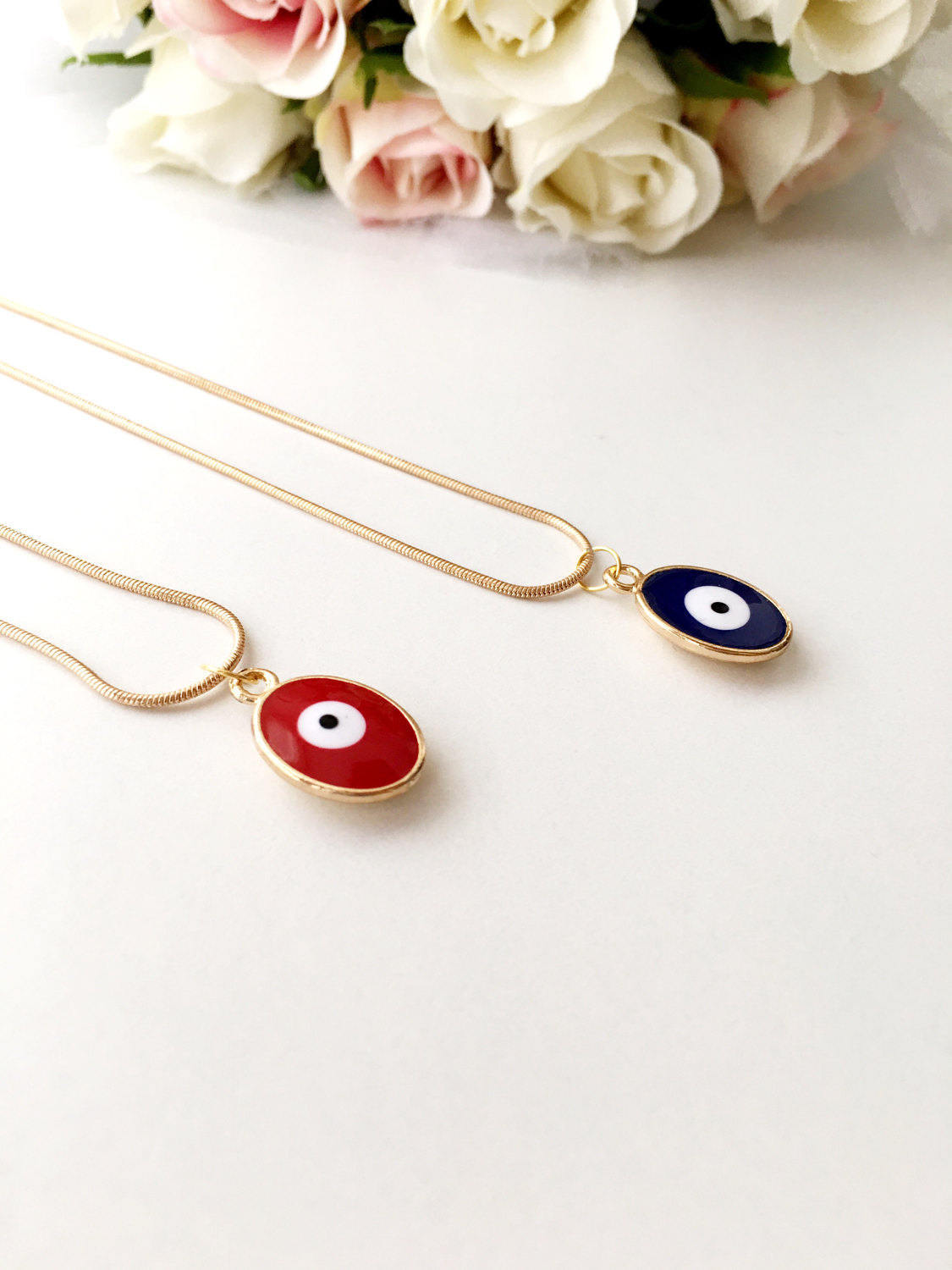 A delicate Tiny Evil Eye Necklace featuring blue and red oval brass beads on a 22K gold plated chain, symbolizing protection and good fortune.