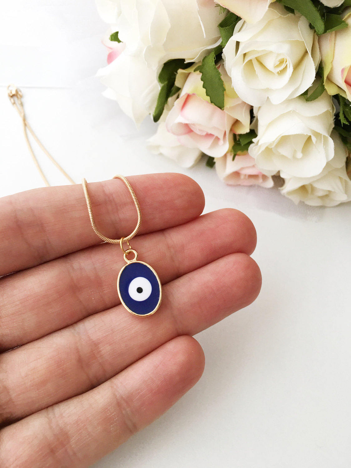 A delicate Tiny Evil Eye Necklace featuring blue and red oval brass beads on a 22K gold plated chain, symbolizing protection and good fortune.