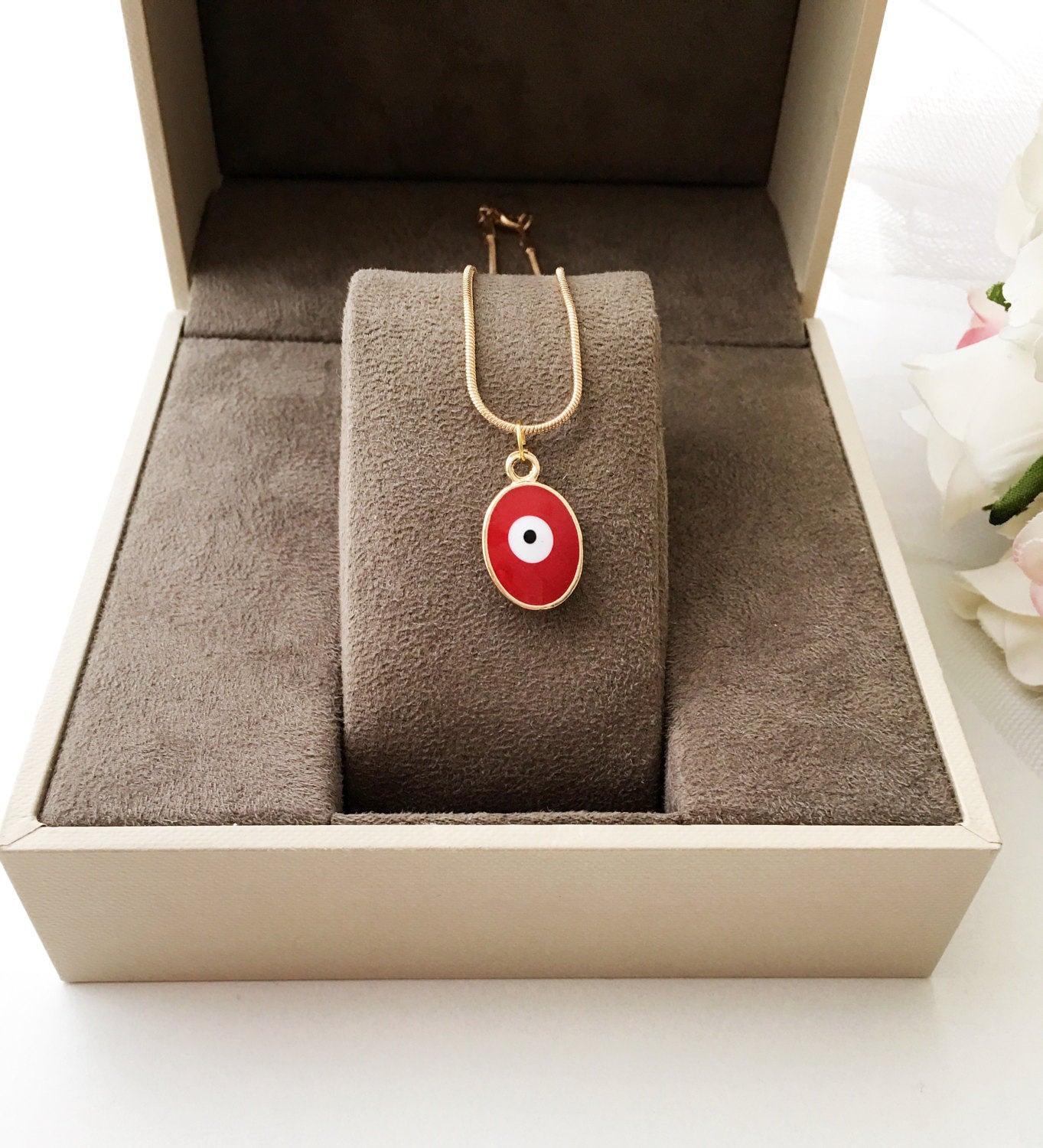 A delicate Tiny Evil Eye Necklace featuring blue and red oval brass beads on a 22K gold plated chain, symbolizing protection and good fortune.