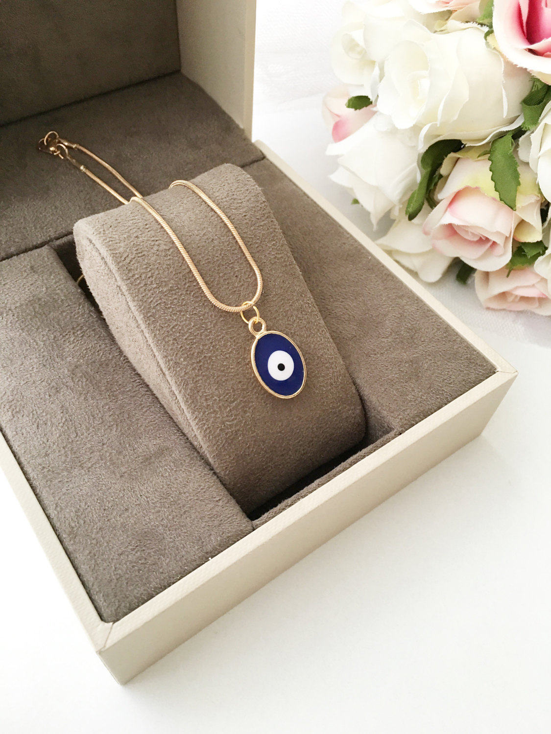 A delicate Tiny Evil Eye Necklace featuring blue and red oval brass beads on a 22K gold plated chain, symbolizing protection and good fortune.