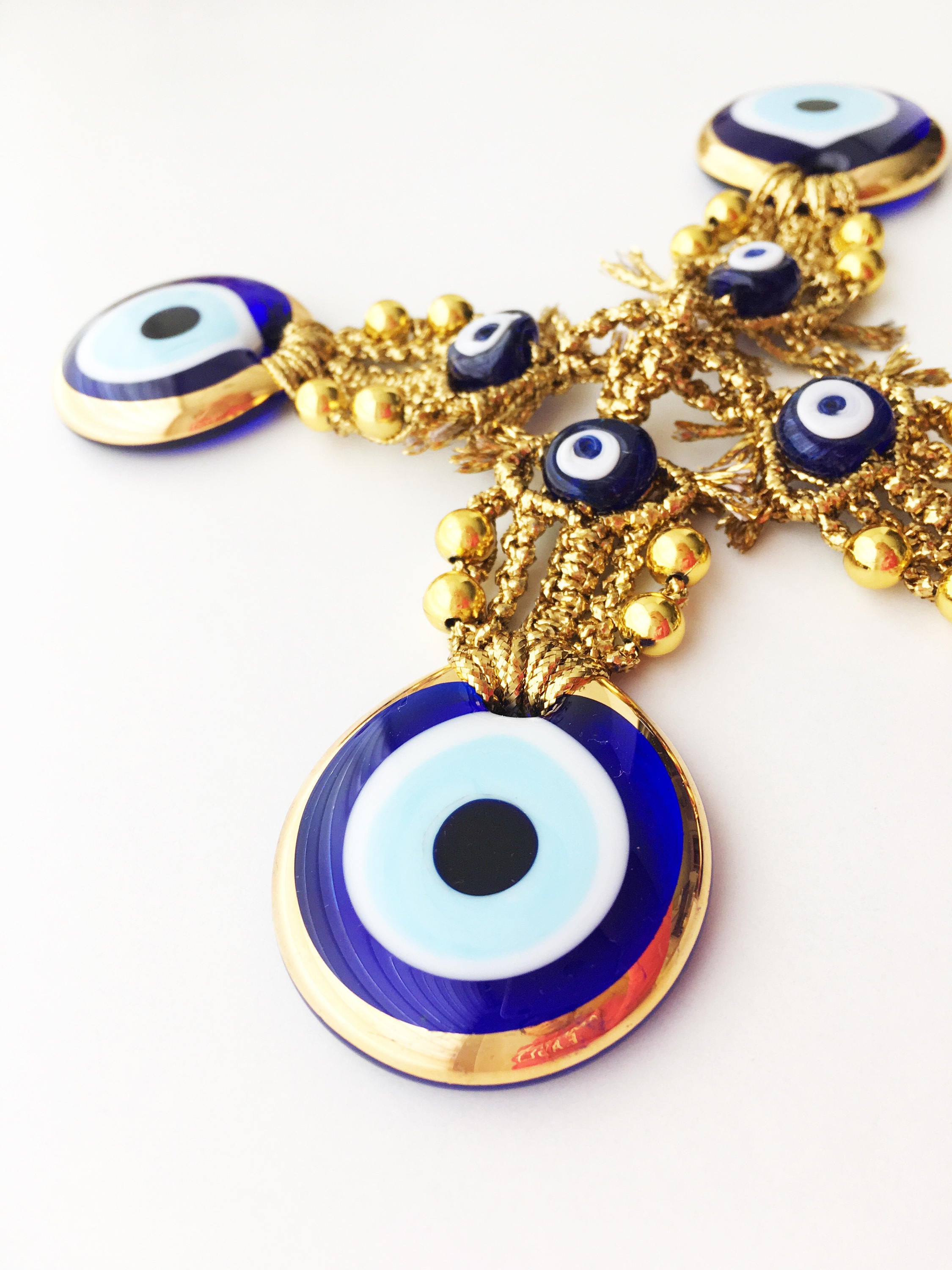 A beautiful Tiny Gold Evil Eye Wall Hanging featuring gold macrame and a large evil eye bead, perfect for home decor or gifting.