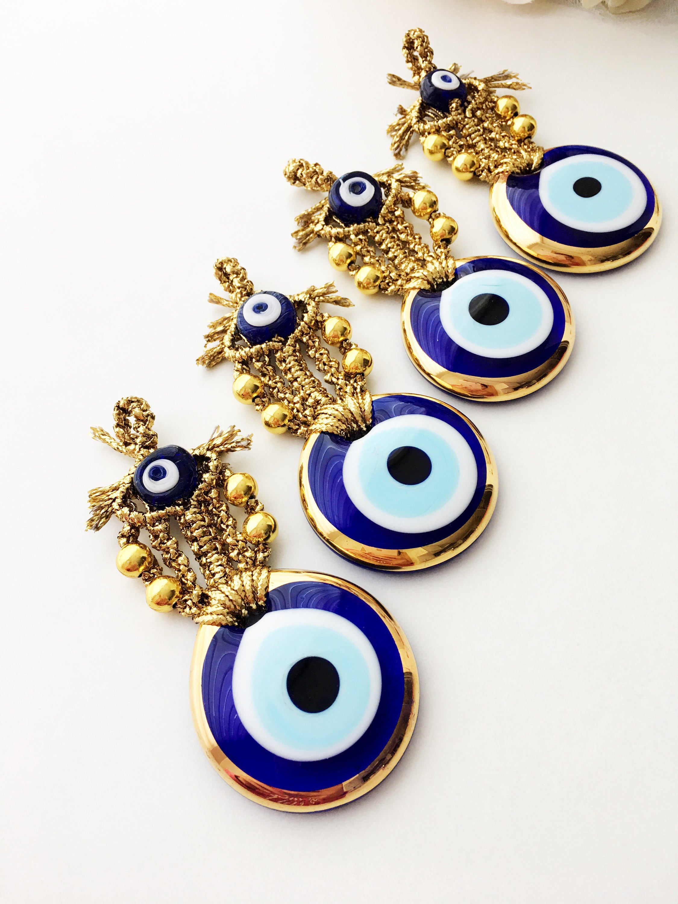 A beautiful Tiny Gold Evil Eye Wall Hanging featuring gold macrame and a large evil eye bead, perfect for home decor or gifting.