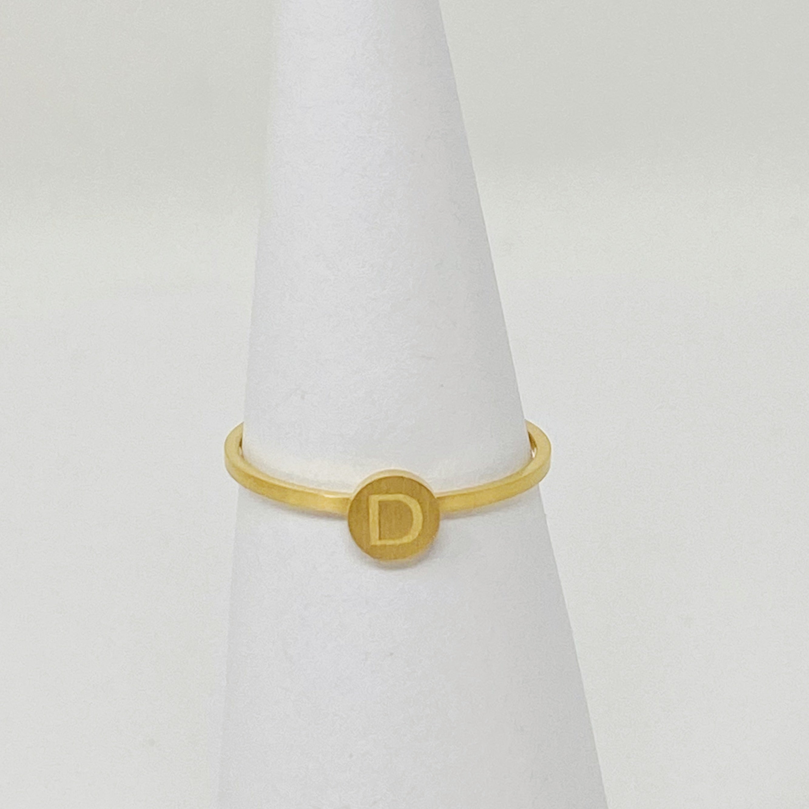 A delicate Tiny Initial Ring featuring a monogrammed initial, crafted from stainless steel with an 18K gold plated finish.