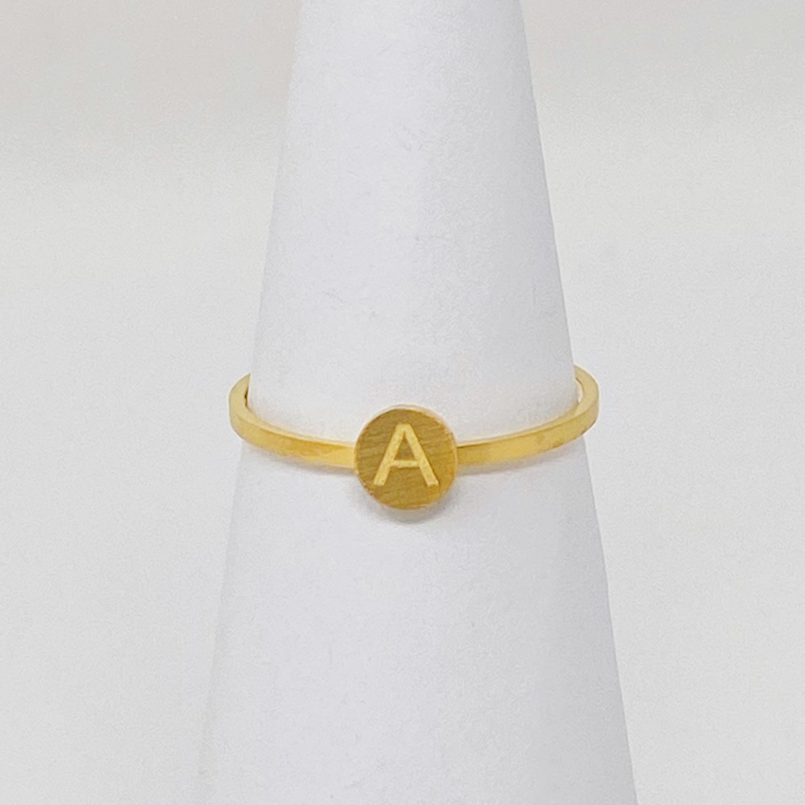 A delicate Tiny Initial Ring featuring a monogrammed initial, crafted from stainless steel with an 18K gold plated finish.