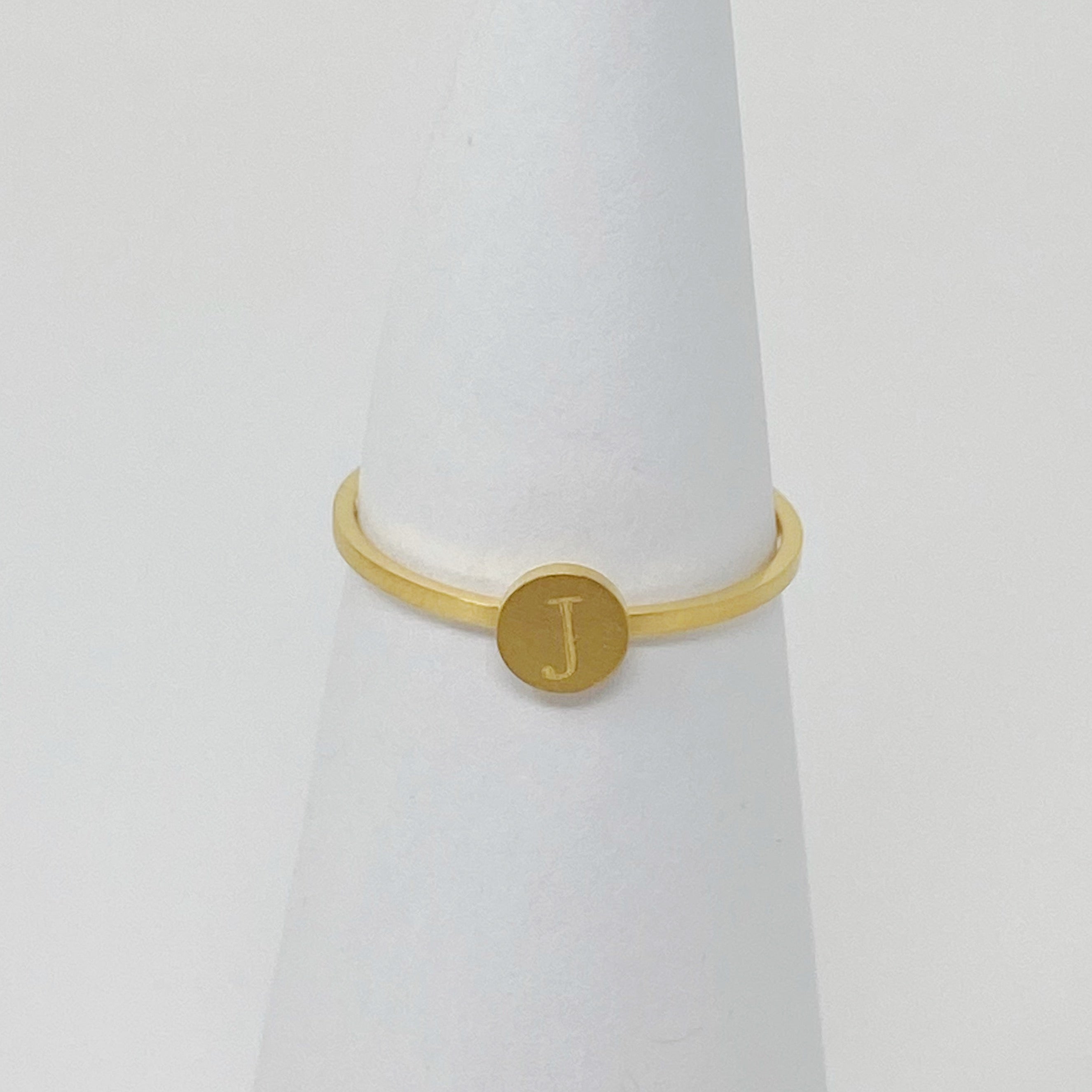 A delicate Tiny Initial Ring featuring a monogrammed initial, crafted from stainless steel with an 18K gold plated finish.