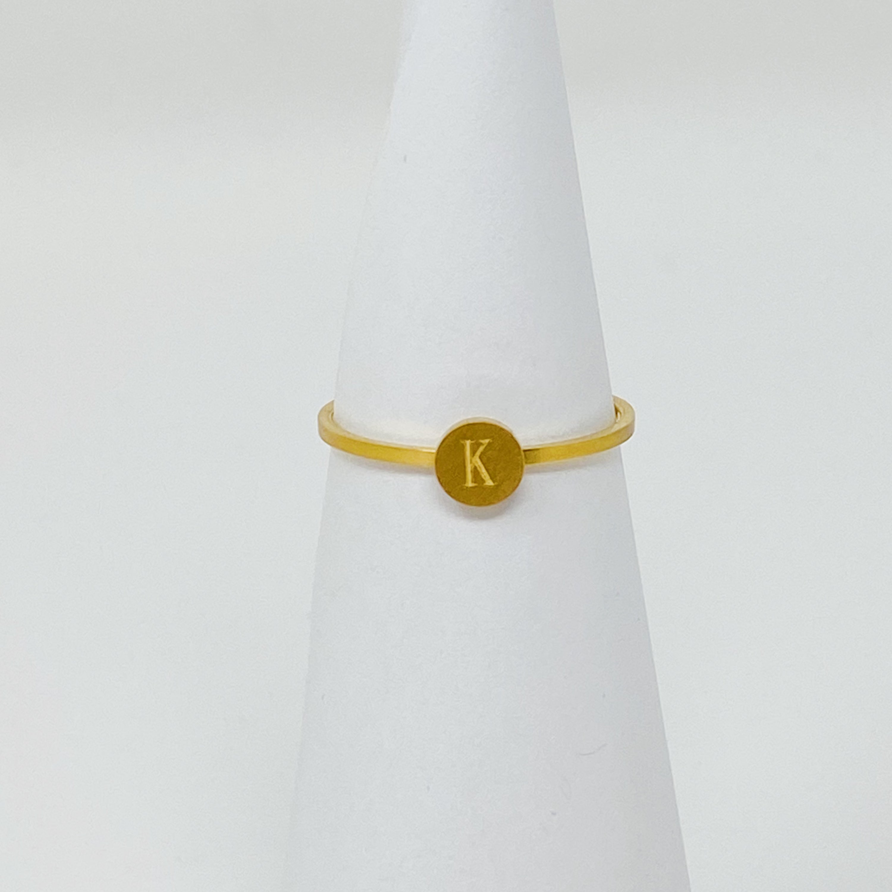 A delicate Tiny Initial Ring featuring a monogrammed initial, crafted from stainless steel with an 18K gold plated finish.