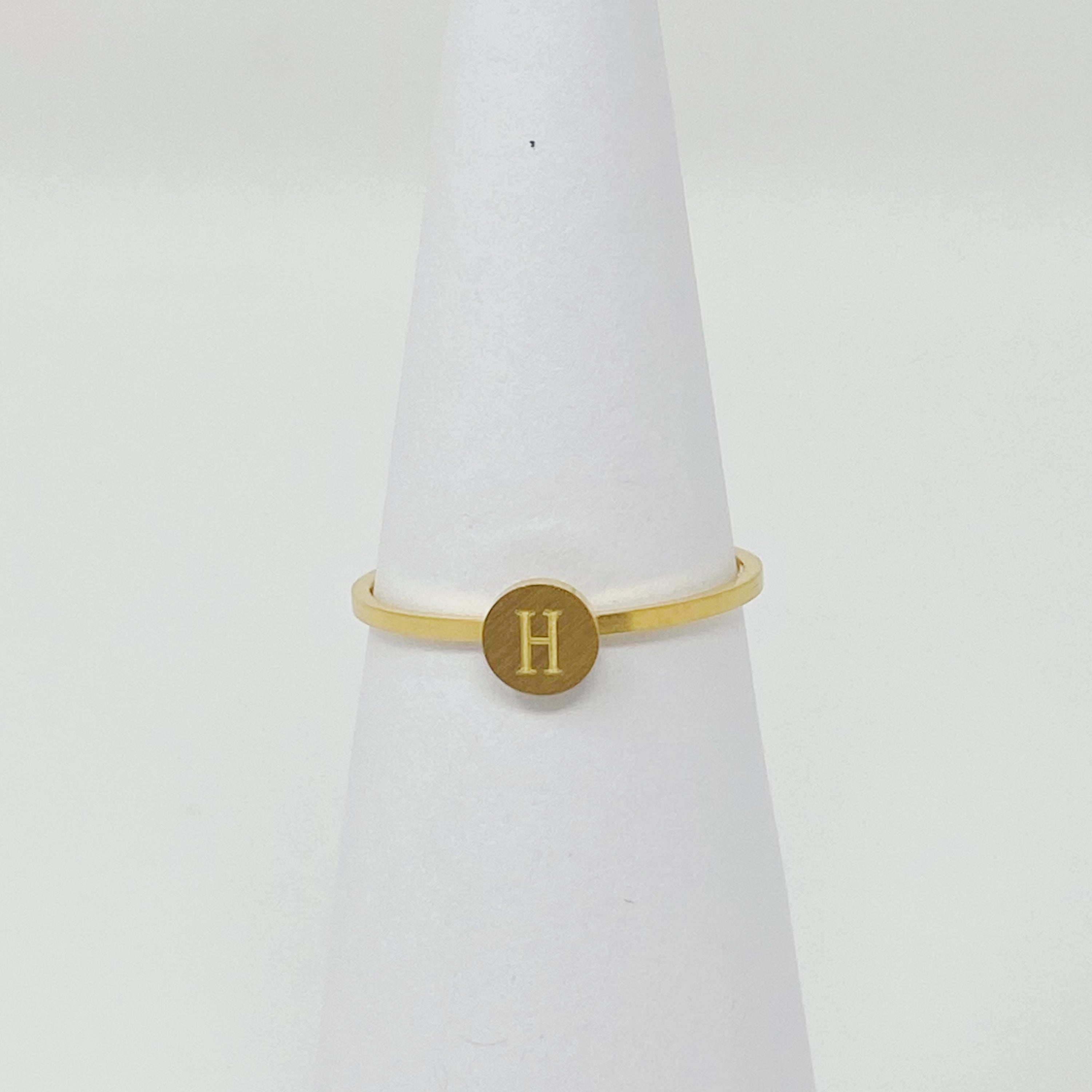 A delicate Tiny Initial Ring featuring a monogrammed initial, crafted from stainless steel with an 18K gold plated finish.