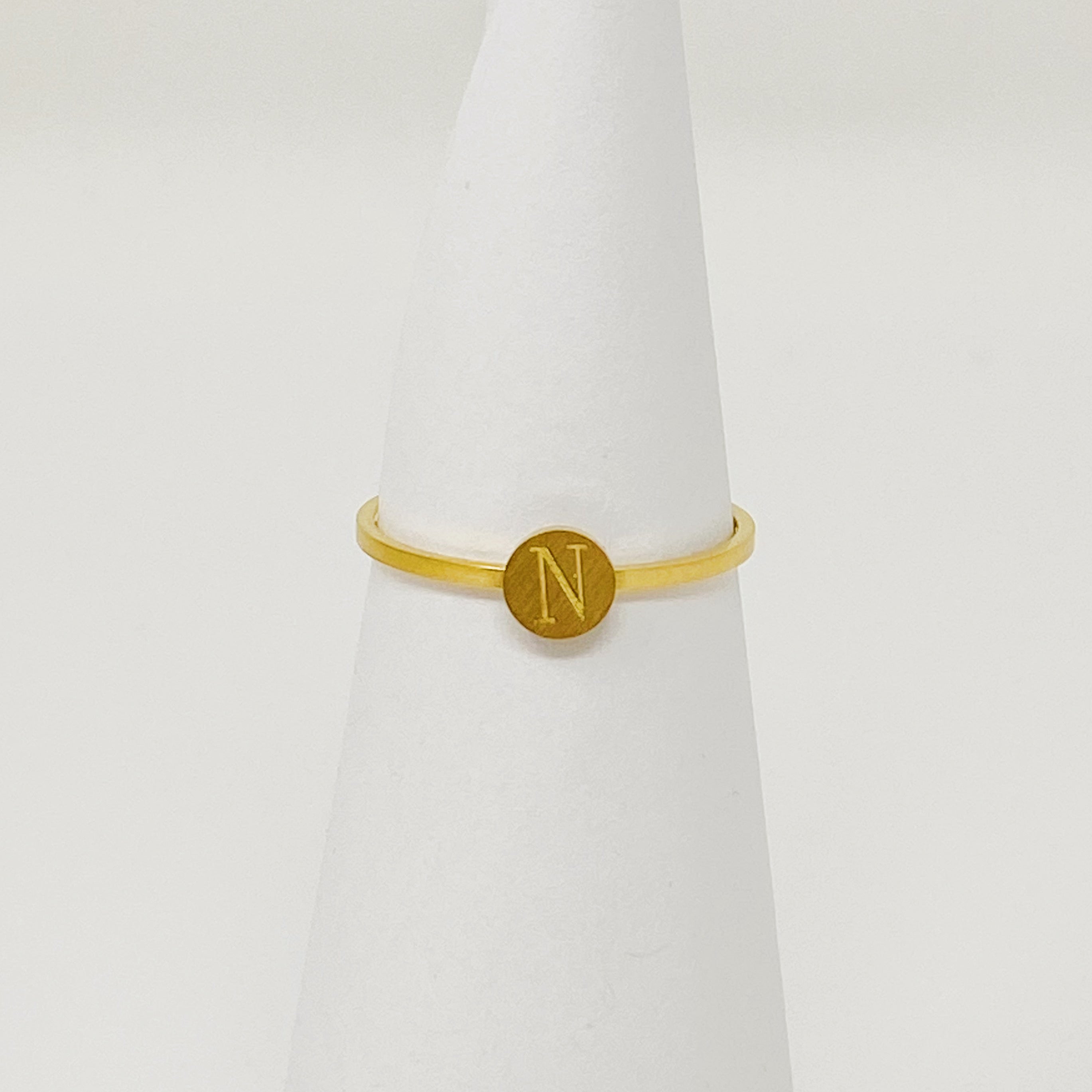 A delicate Tiny Initial Ring featuring a monogrammed initial, crafted from stainless steel with an 18K gold plated finish.