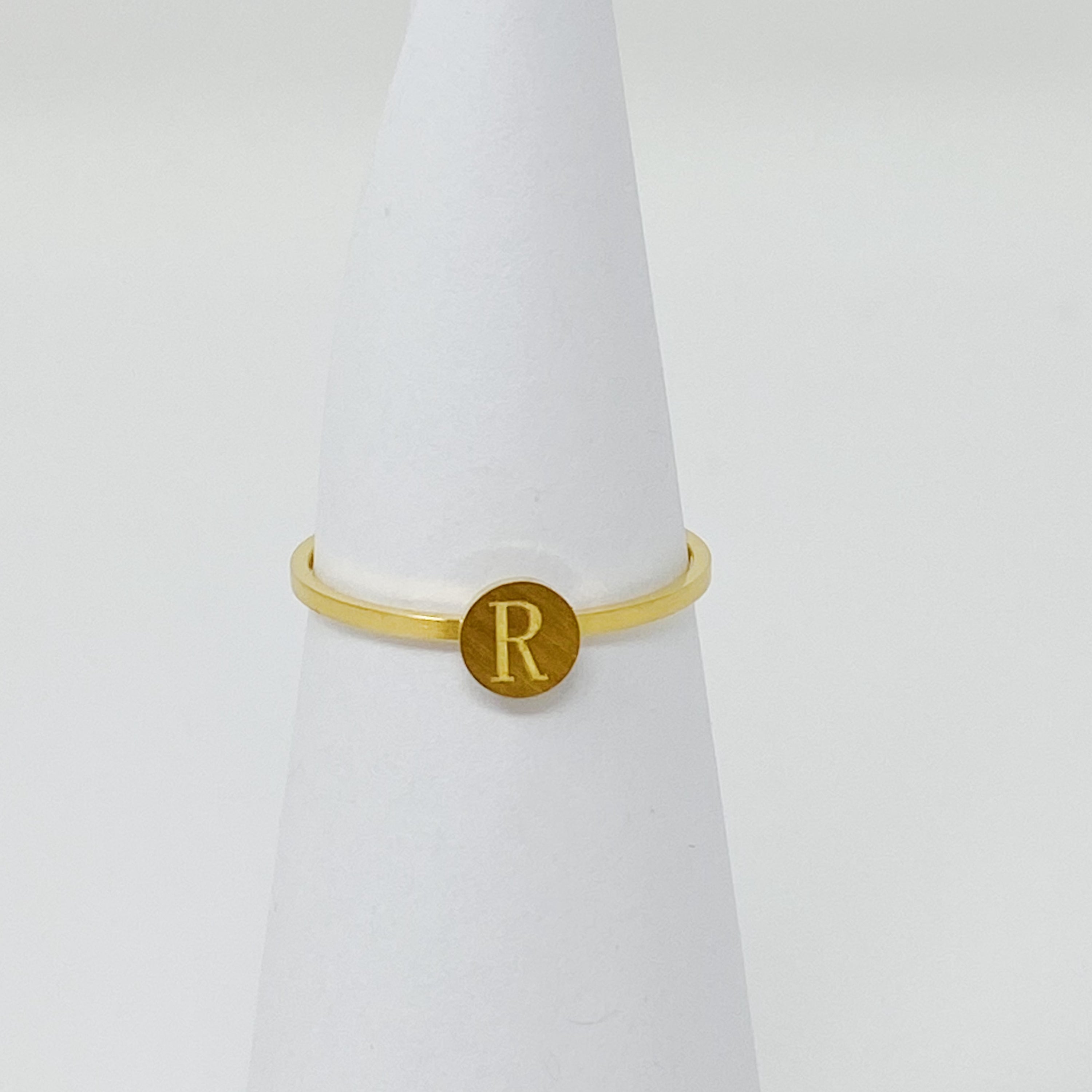 A delicate Tiny Initial Ring featuring a monogrammed initial, crafted from stainless steel with an 18K gold plated finish.