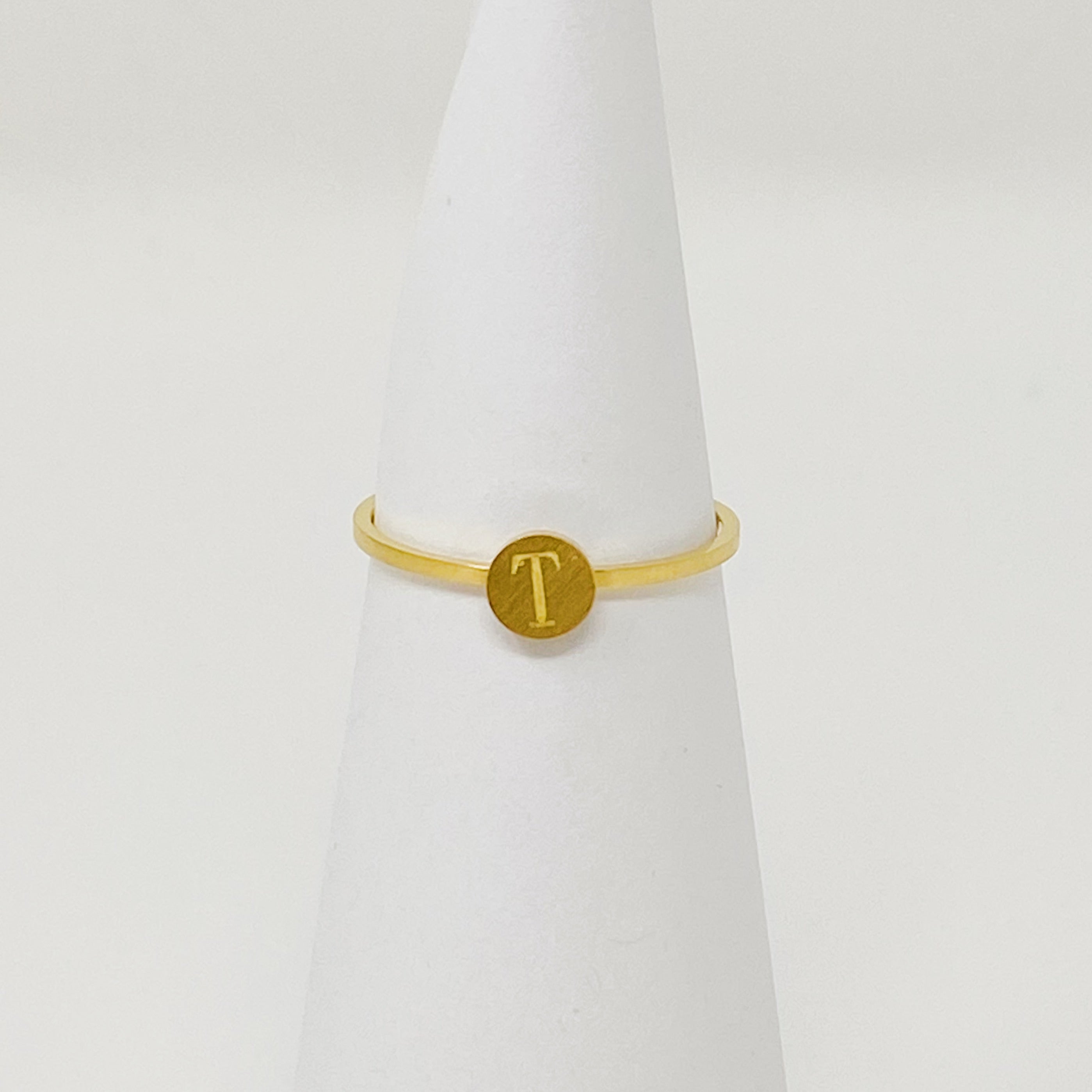 A delicate Tiny Initial Ring featuring a monogrammed initial, crafted from stainless steel with an 18K gold plated finish.