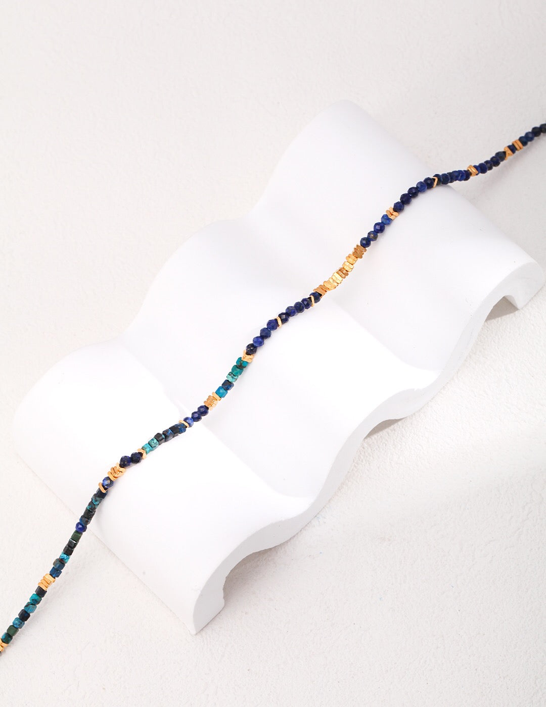 A delicate Tiny Lapis Lazuli Beaded Necklace featuring small blue beads and gold vermeil accents, elegantly displayed on a soft background.