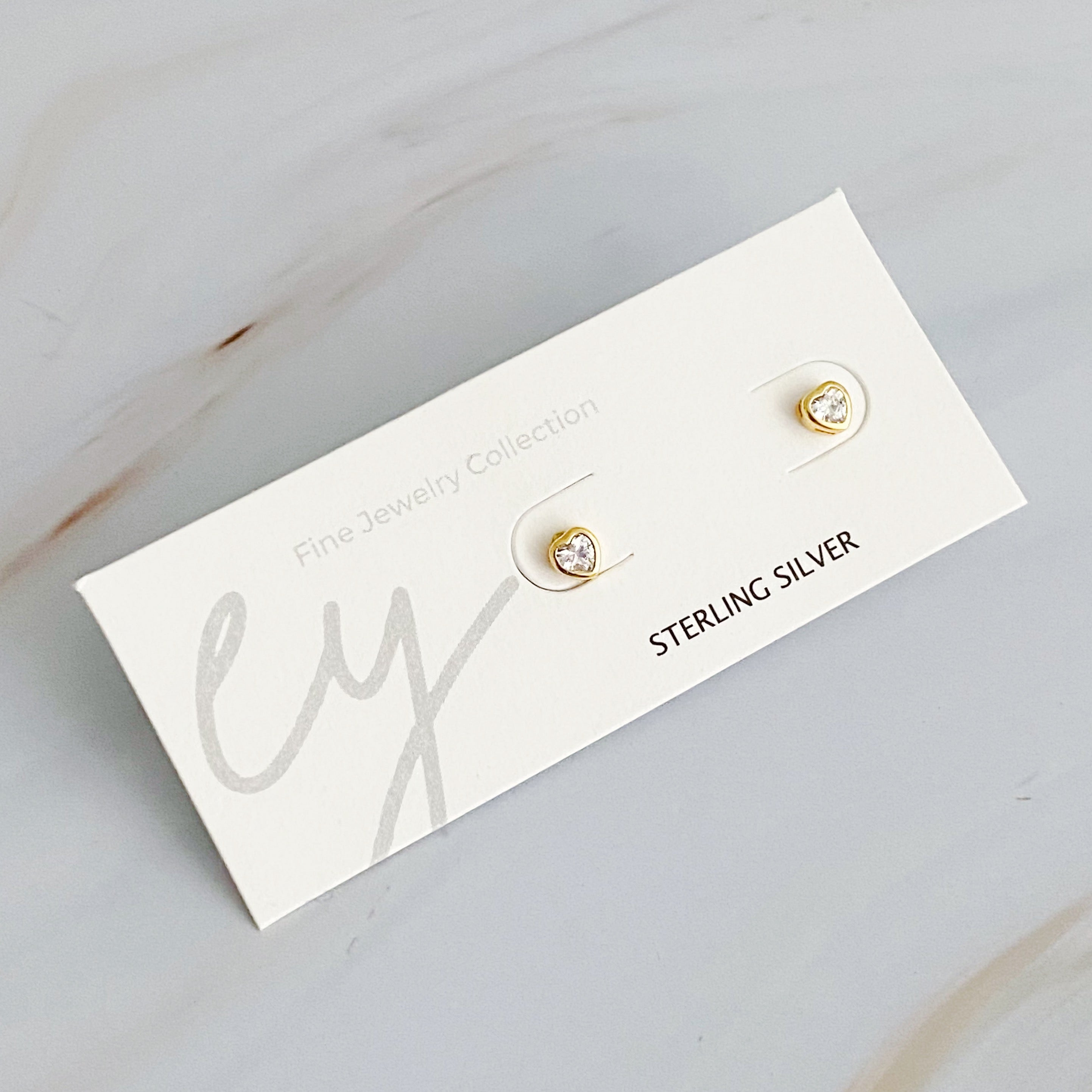 Tiny Shape Tiny Stud Sterling Silver Earrings featuring heart and flip flop designs, elegantly displayed on a logo card.