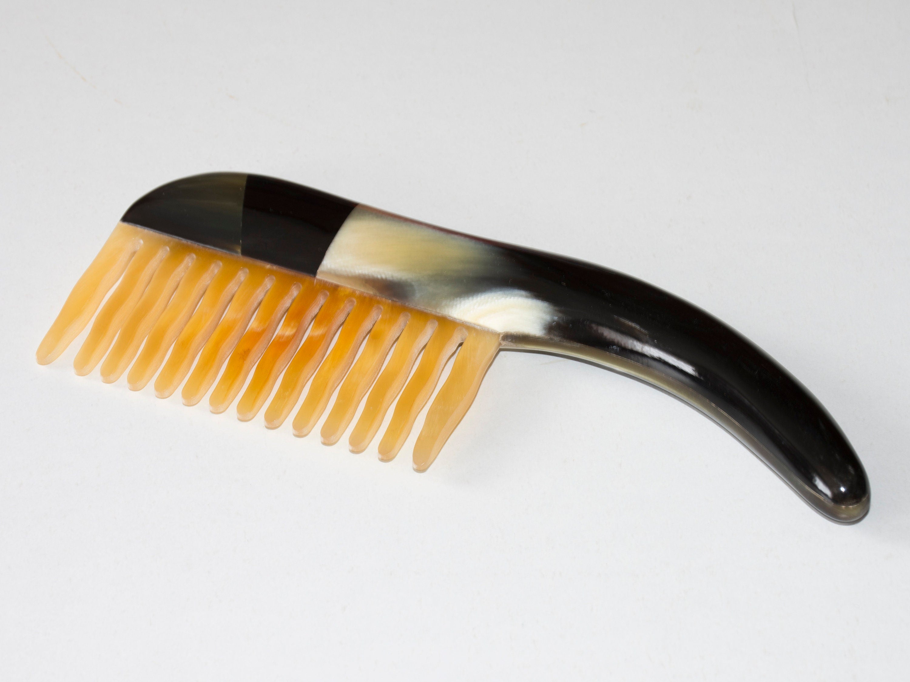 A beautifully crafted Tortoise Hair Comb made from organic horn, featuring a unique pattern and a comfortable handle.