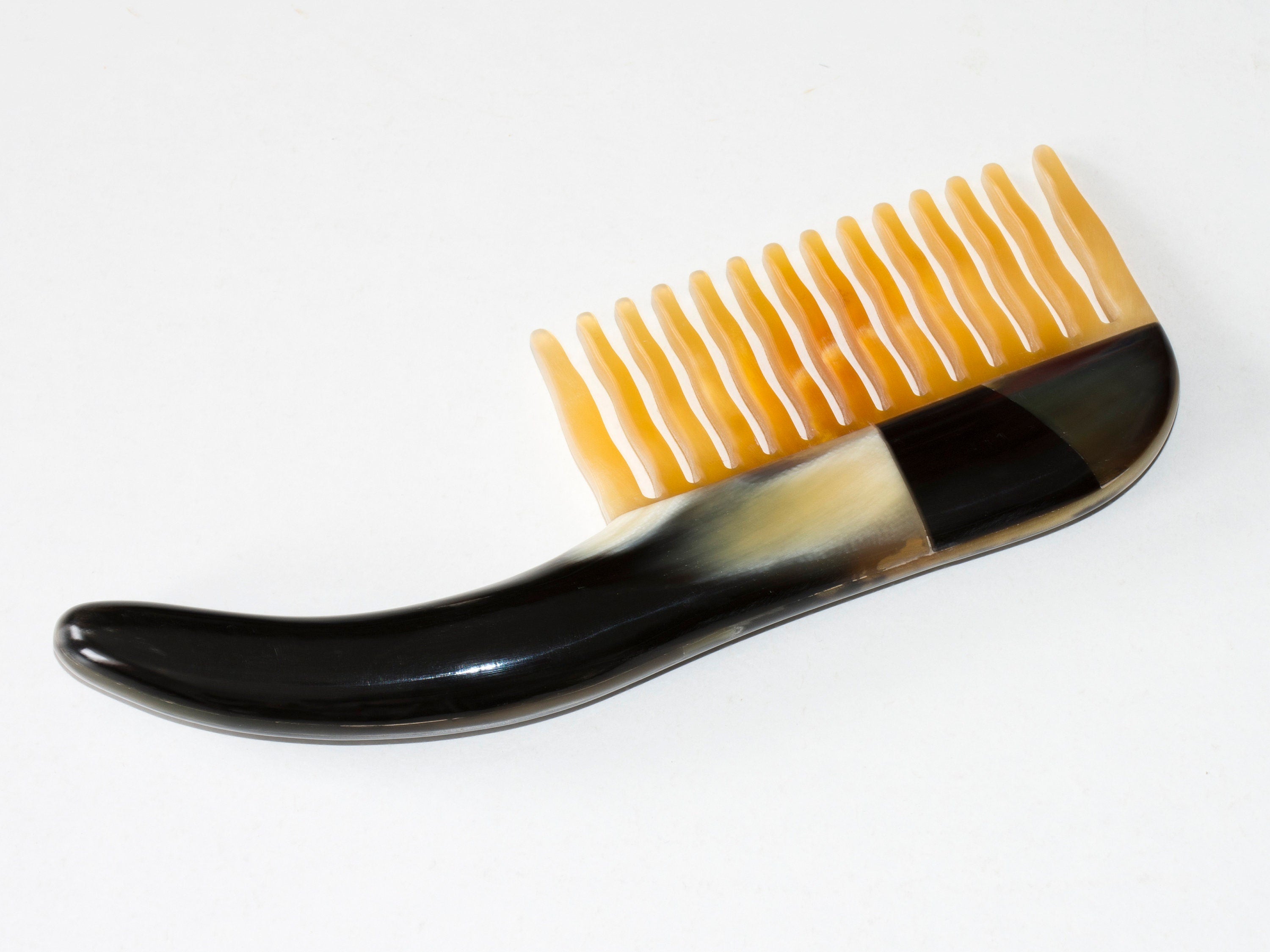 A beautifully crafted Tortoise Hair Comb made from organic horn, featuring a unique pattern and a comfortable handle.