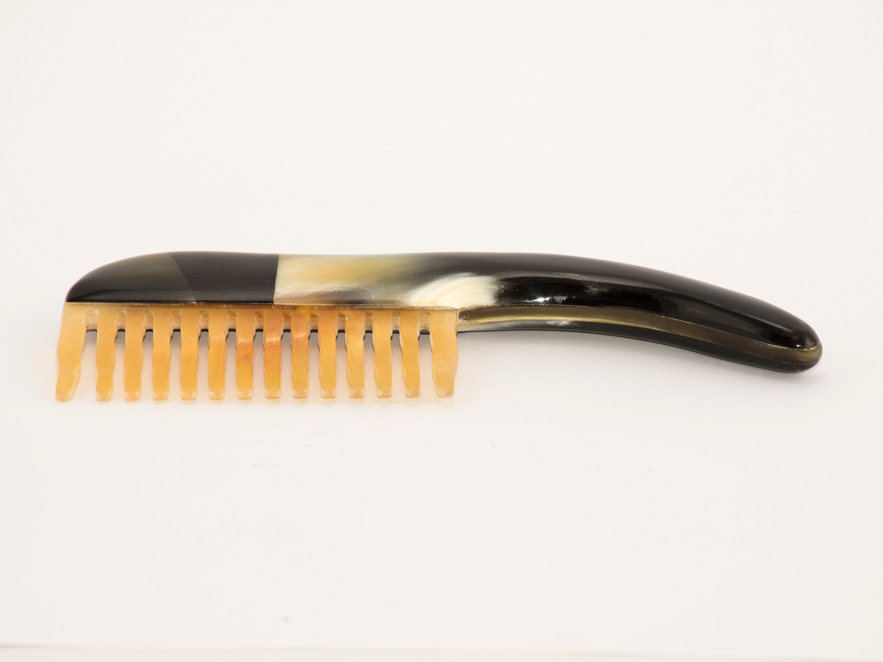 A beautifully crafted Tortoise Hair Comb made from organic horn, featuring a unique pattern and a comfortable handle.