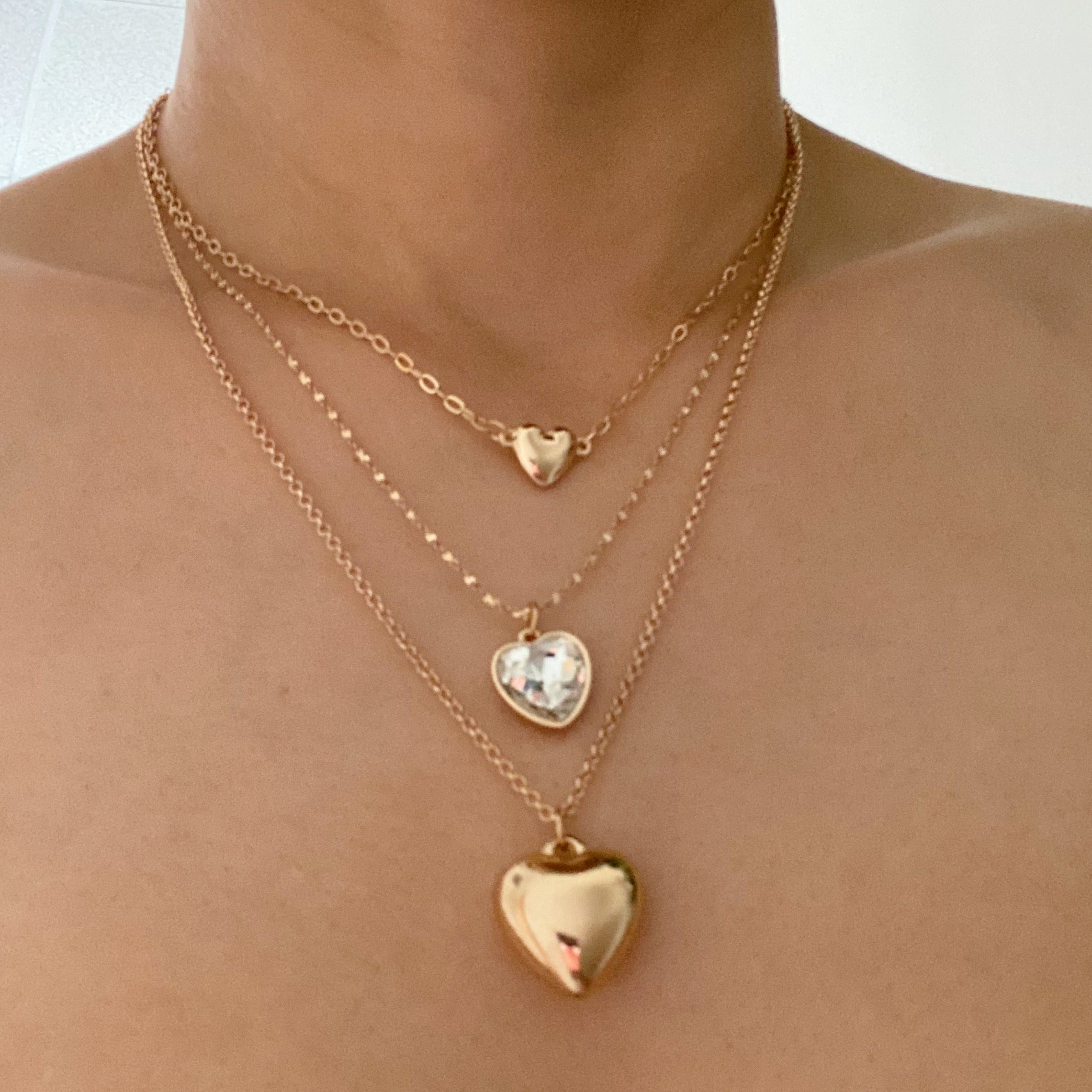 Triple heart pendant necklace set featuring three necklaces with heart-shaped pendants in varying sizes and chain lengths.