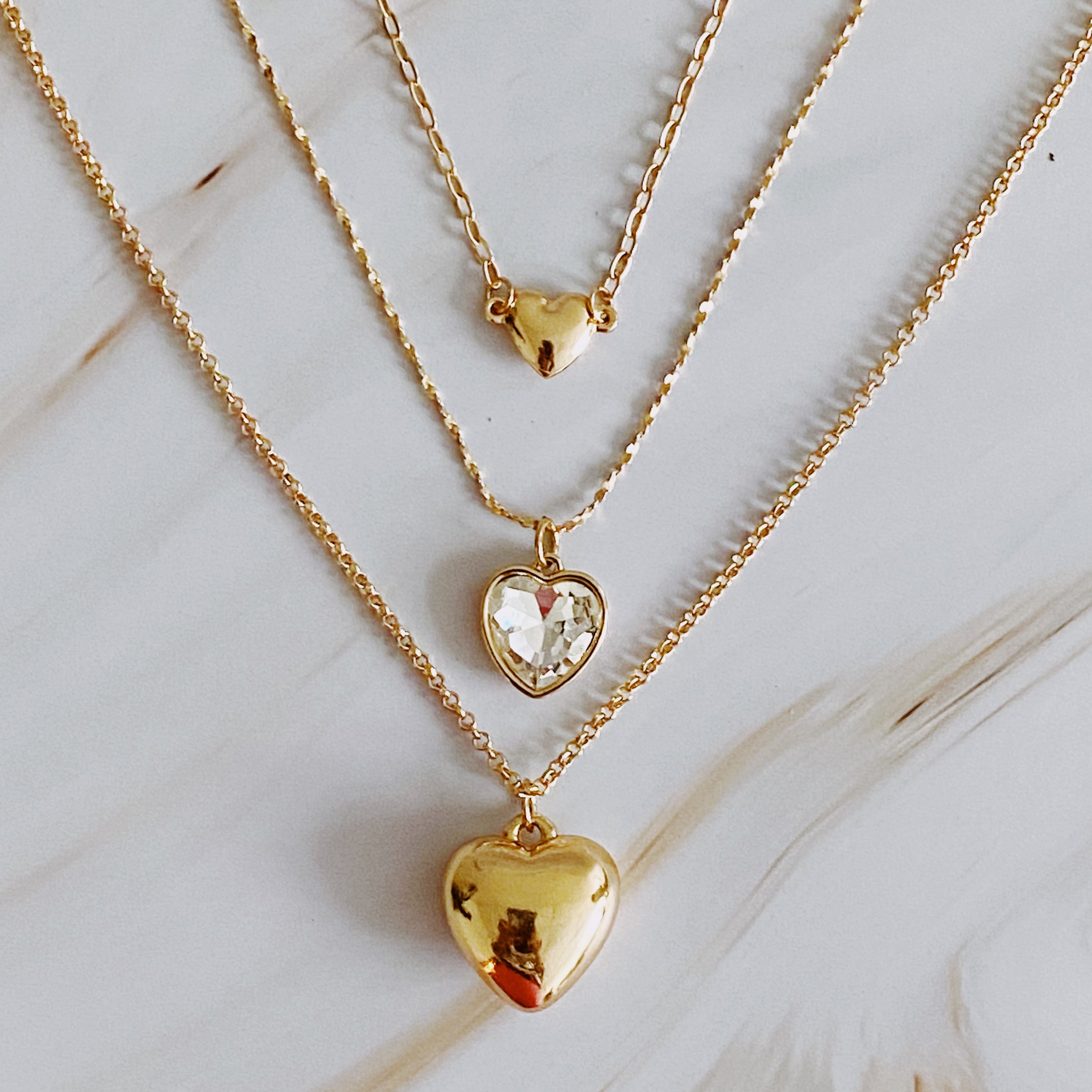 Triple heart pendant necklace set featuring three necklaces with heart-shaped pendants in varying sizes and chain lengths.