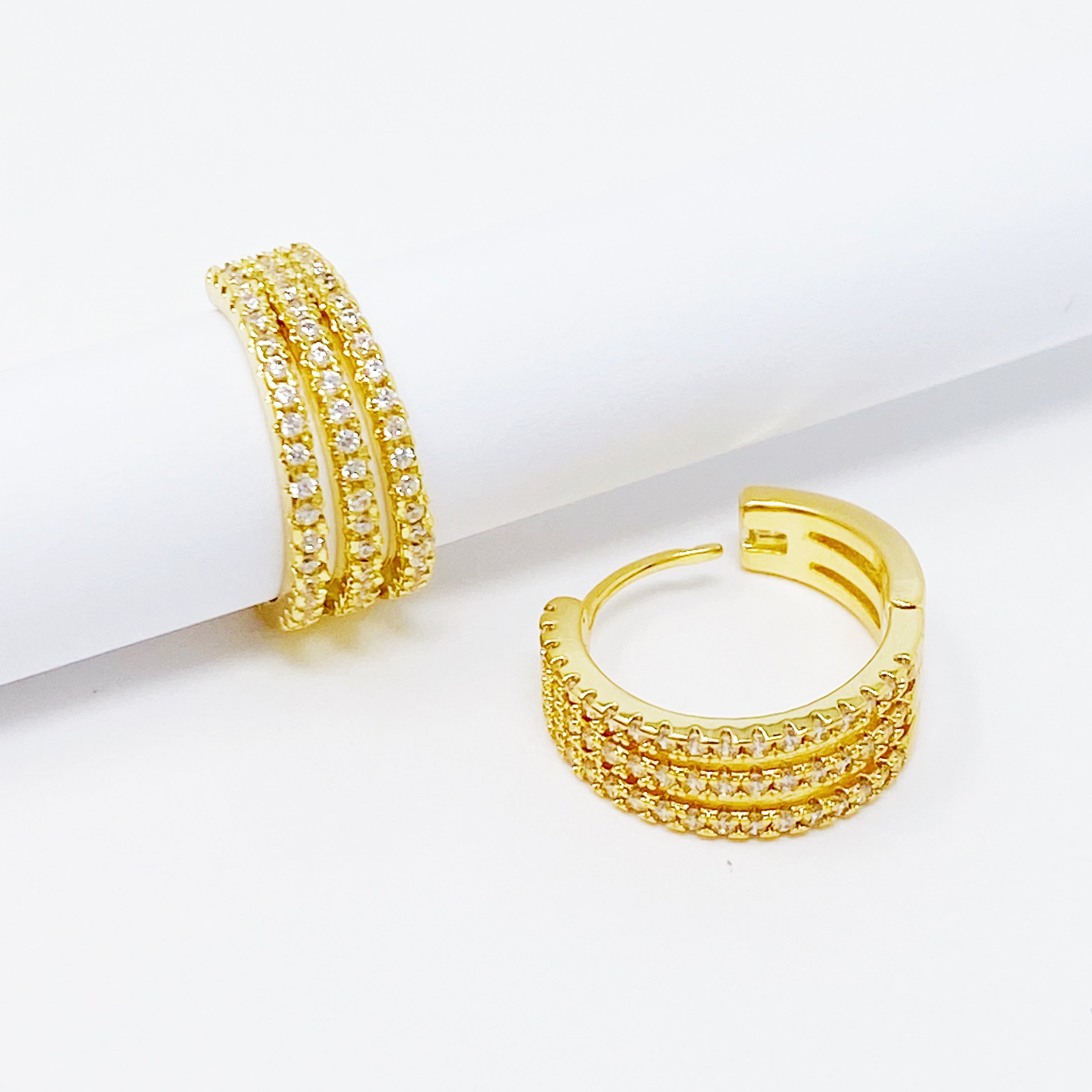 Elegant Triple Shine Huggie Earrings featuring cubic zirconia and gold plated brass, perfect for any occasion.