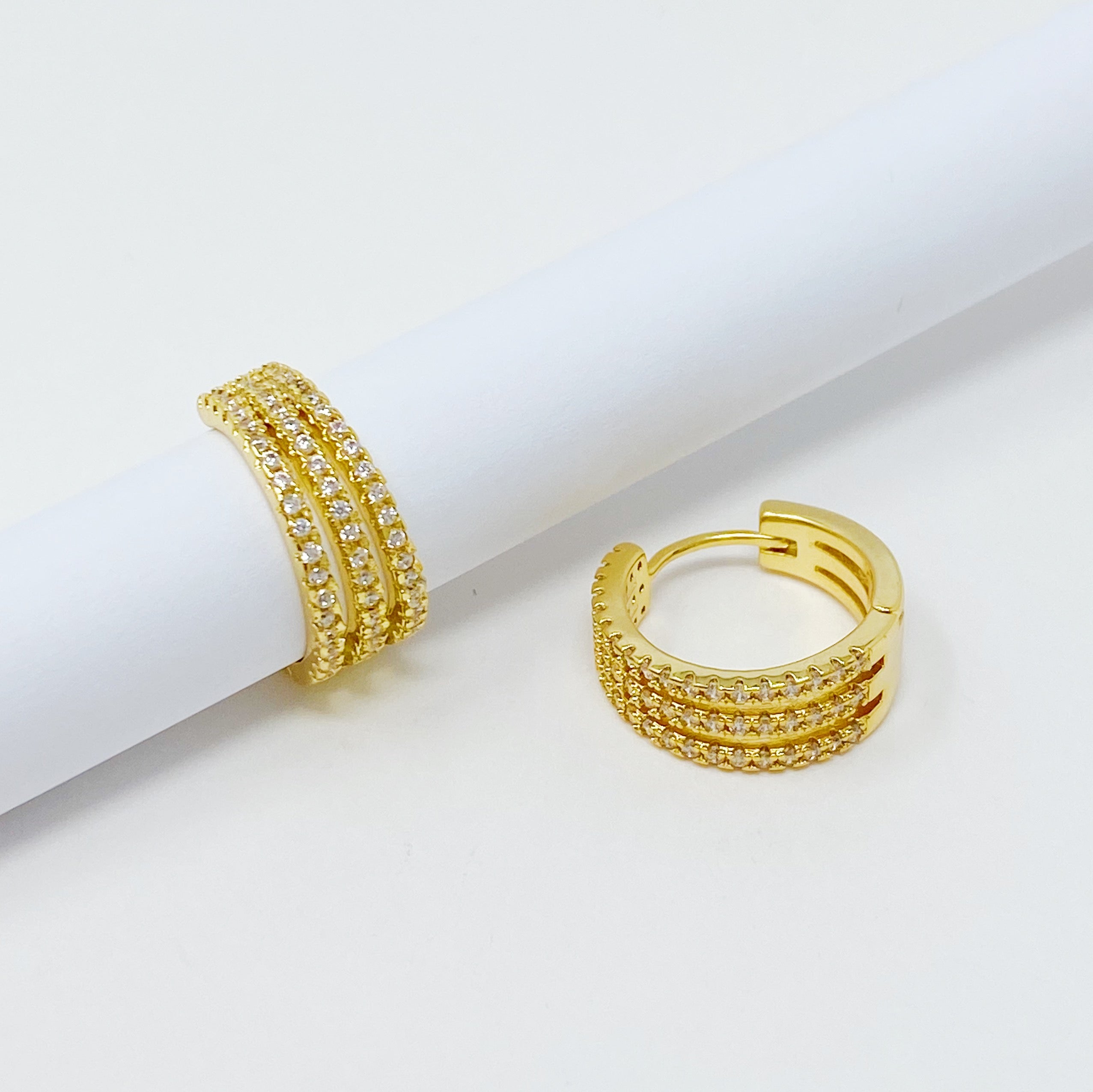 Elegant Triple Shine Huggie Earrings featuring cubic zirconia and gold plated brass, perfect for any occasion.