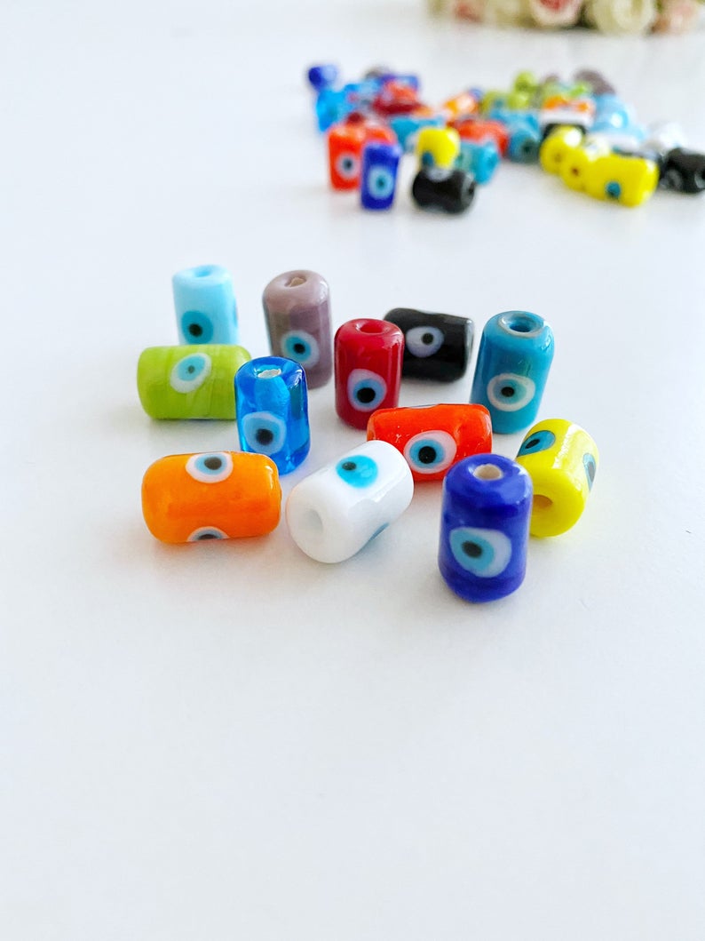 A collection of colorful Tube Evil Eye Murano Beads in various shades including blue, red, and green, showcasing their unique designs and craftsmanship.