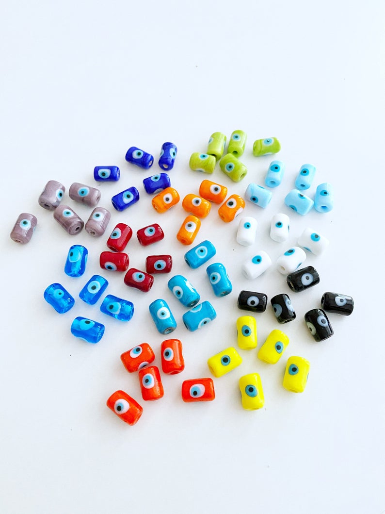 A collection of colorful Tube Evil Eye Murano Beads in various shades including blue, red, and green, showcasing their unique designs and craftsmanship.