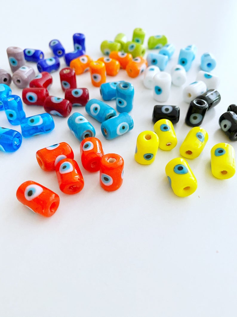 A collection of colorful Tube Evil Eye Murano Beads in various shades including blue, red, and green, showcasing their unique designs and craftsmanship.