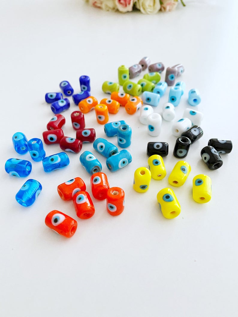 A collection of colorful Tube Evil Eye Murano Beads in various shades including blue, red, and green, showcasing their unique designs and craftsmanship.