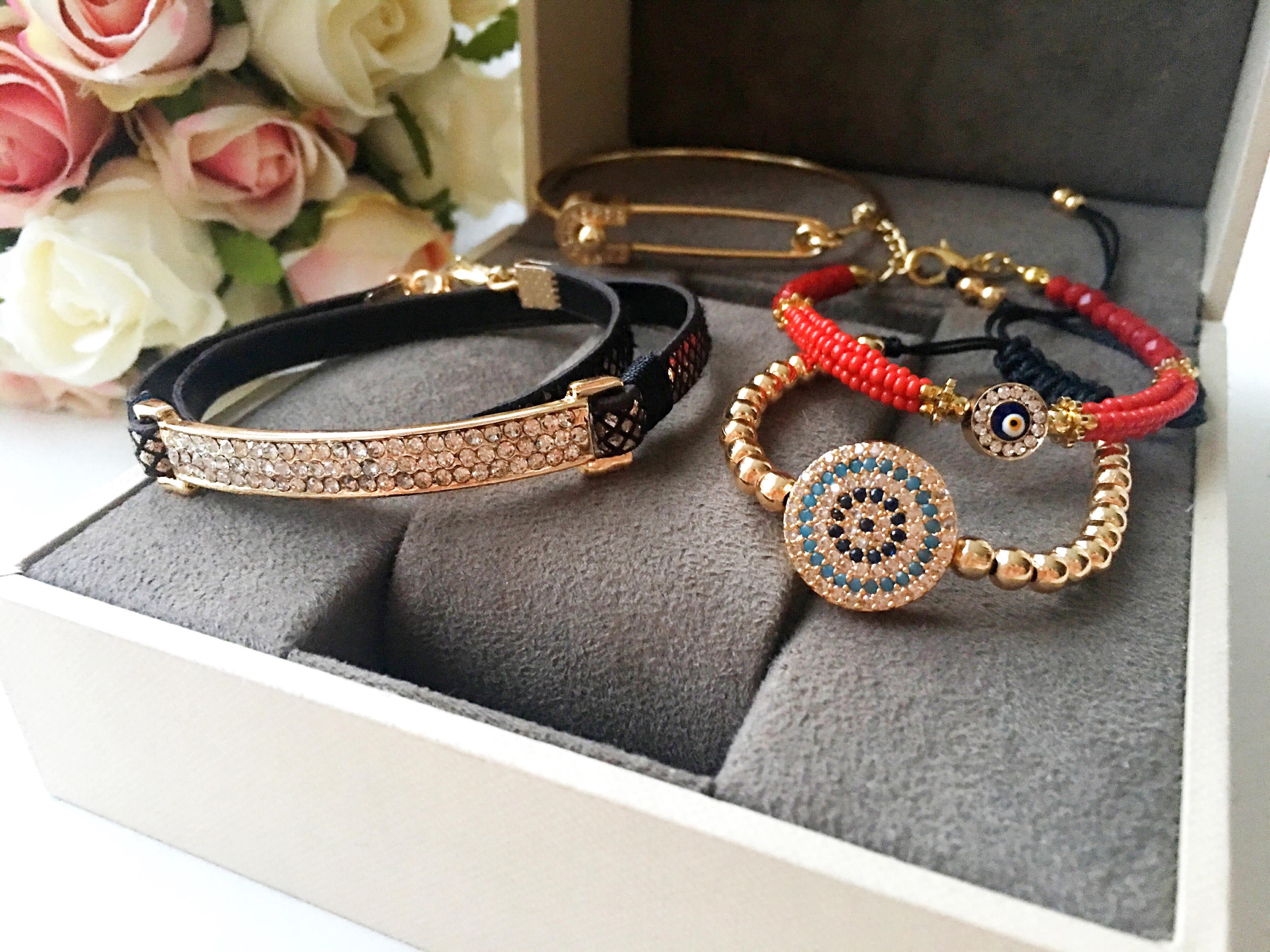 A beautiful set of handmade Turkish evil eye bracelets featuring gold bangles, Miyuki beads, and zirconia leather, showcasing unique designs.