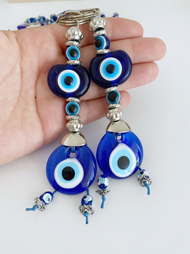 A beautiful Turkish Evil Eye Keychain featuring a blue glass evil eye bead and an oval white bead, symbolizing protection and good luck.