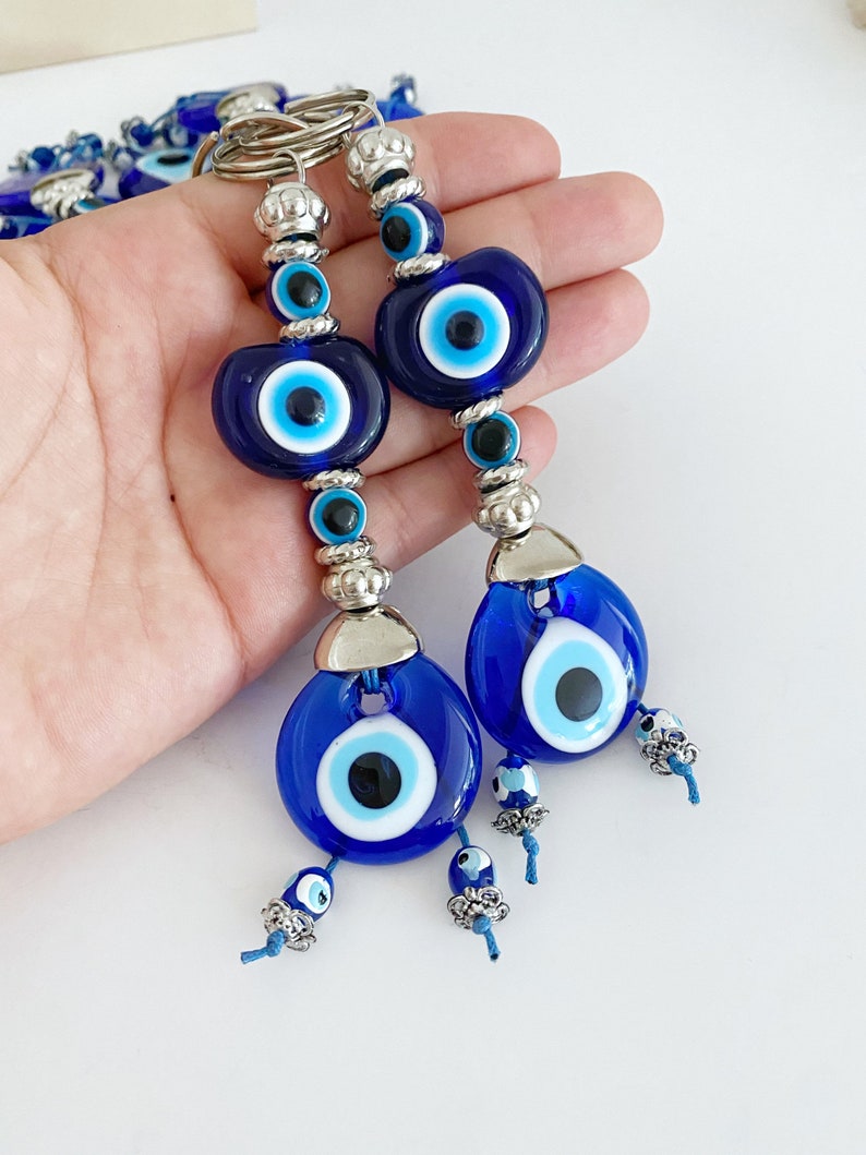 A beautiful Turkish Evil Eye Keychain featuring a blue glass evil eye bead and an oval white bead, symbolizing protection and good luck.