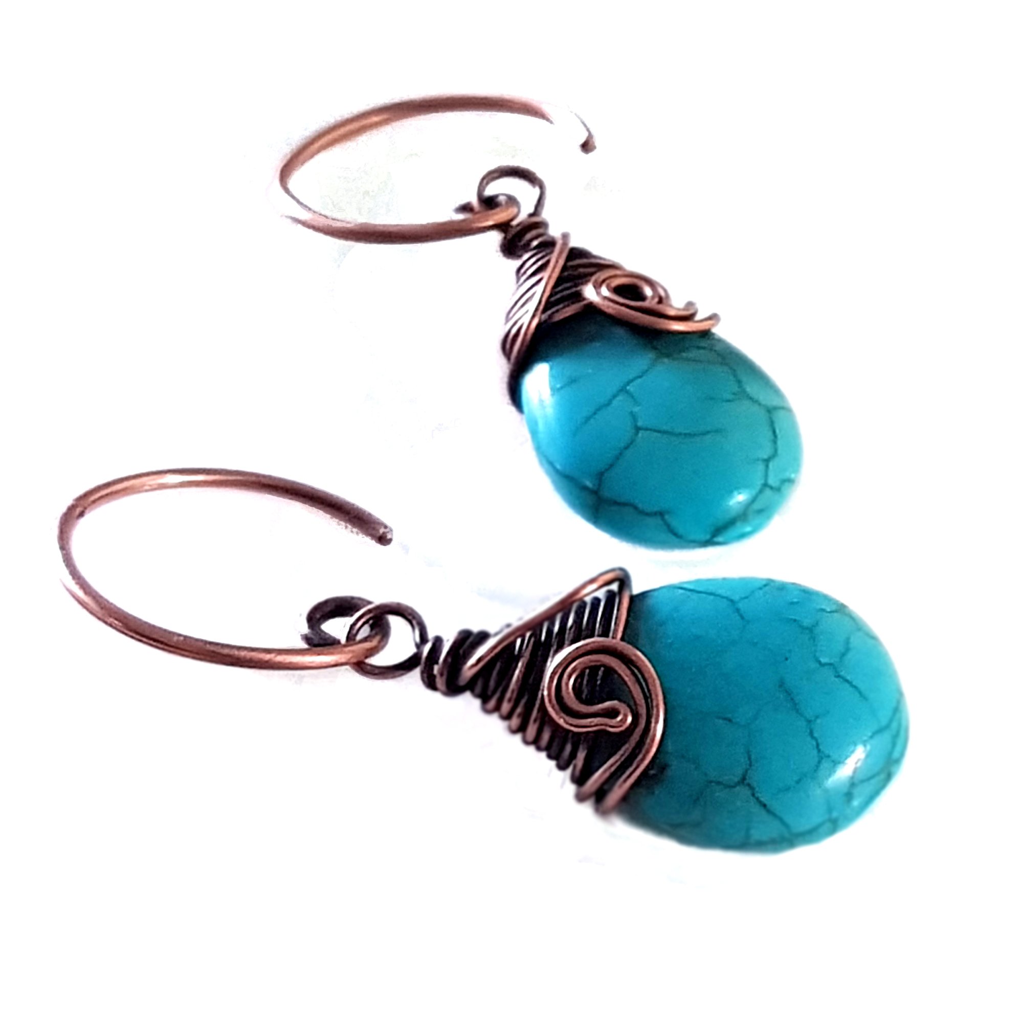 Turquoise blue howlite earrings with copper wire wrapping and handmade circle ear wires, elegantly displayed in a velvet pouch.