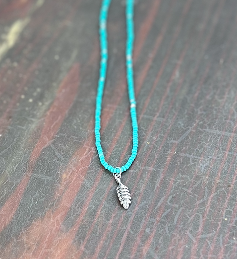 Turquoise Boho Seed Bead Necklace featuring silver beads and a silver feather charm, showcasing a vibrant and stylish design.