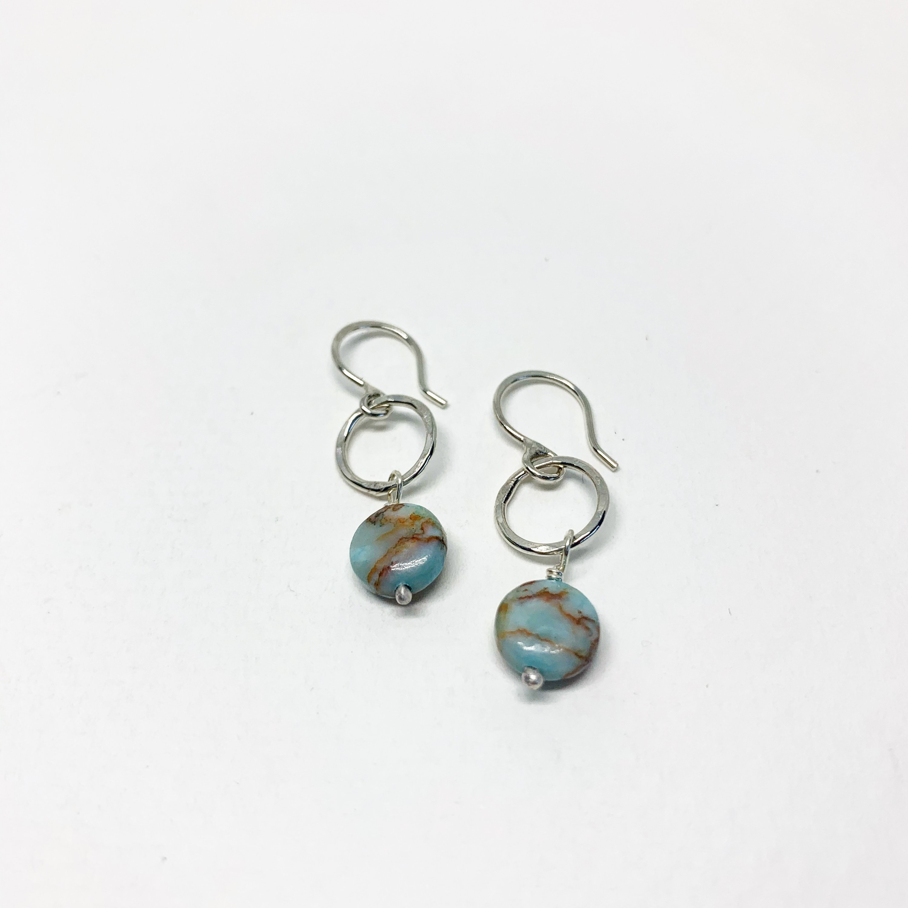 A pair of handmade turquoise disc drop earrings featuring 8mm blue turquoise round discs, hanging from a hammered circle in sterling silver or yellow gold fill.