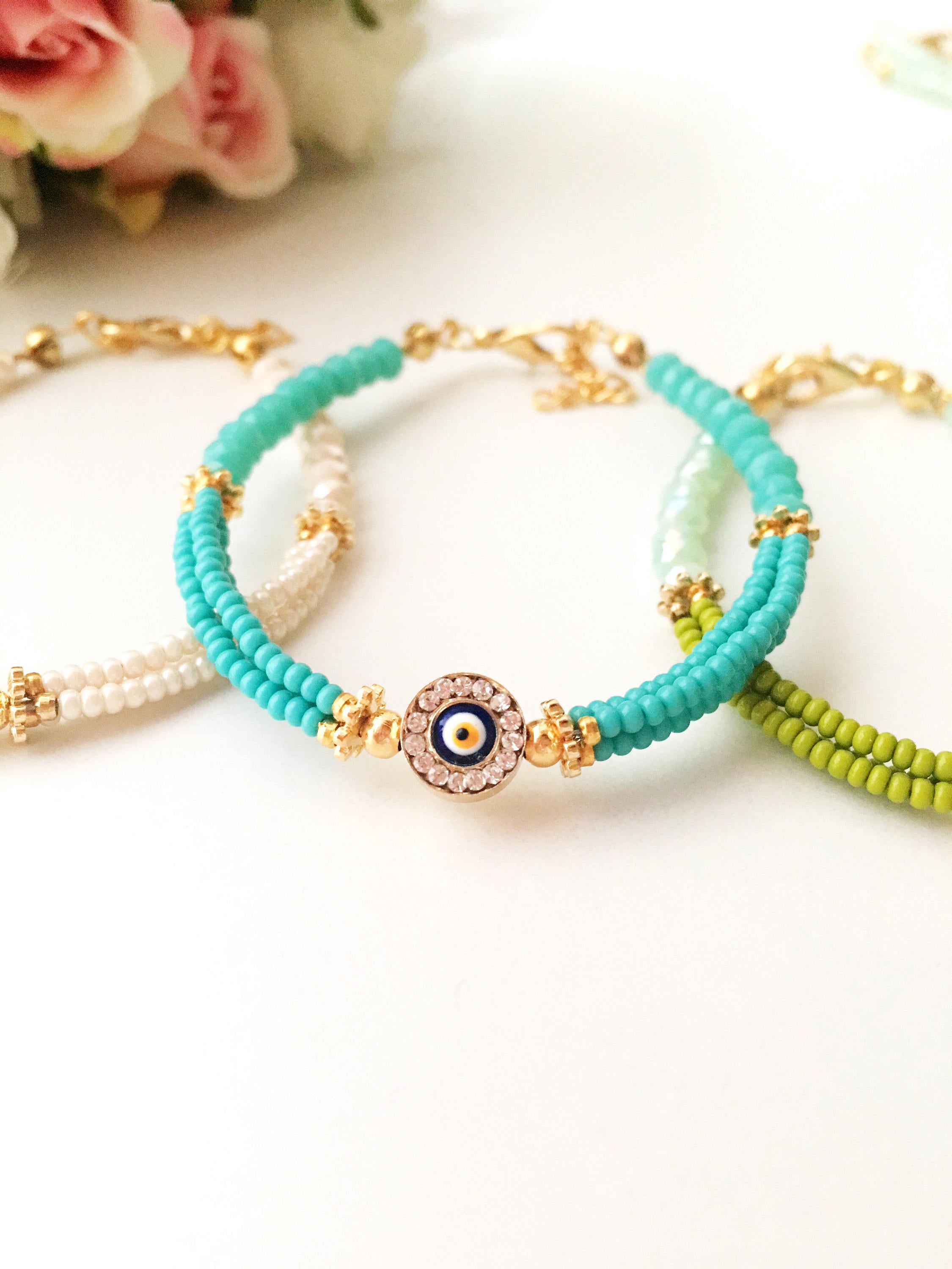 Handmade turquoise seed beads bracelet featuring an evil eye design, showcasing vibrant colors and intricate craftsmanship.