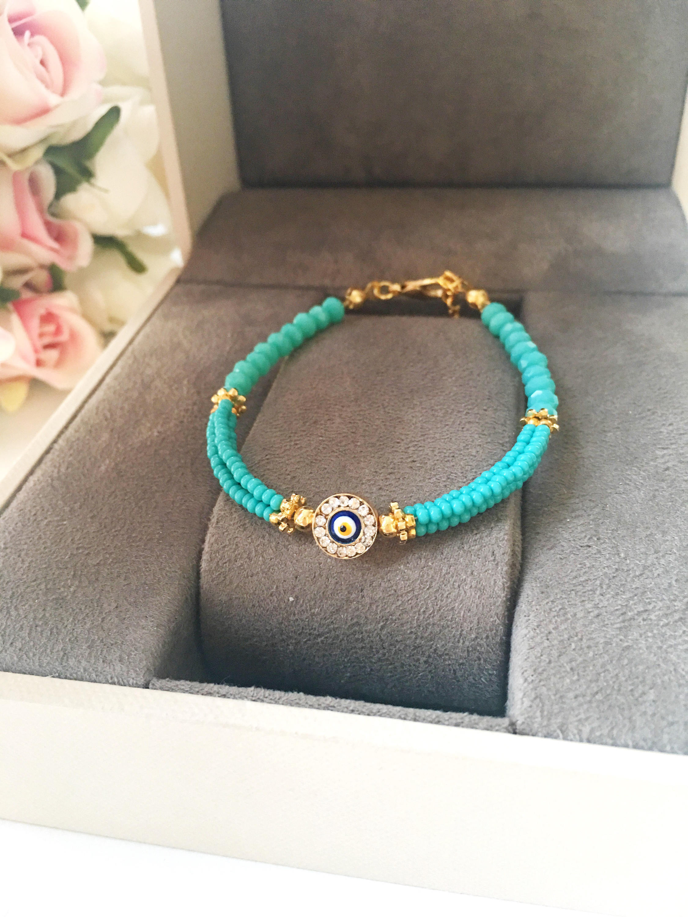 Handmade turquoise seed beads bracelet featuring an evil eye design, showcasing vibrant colors and intricate craftsmanship.