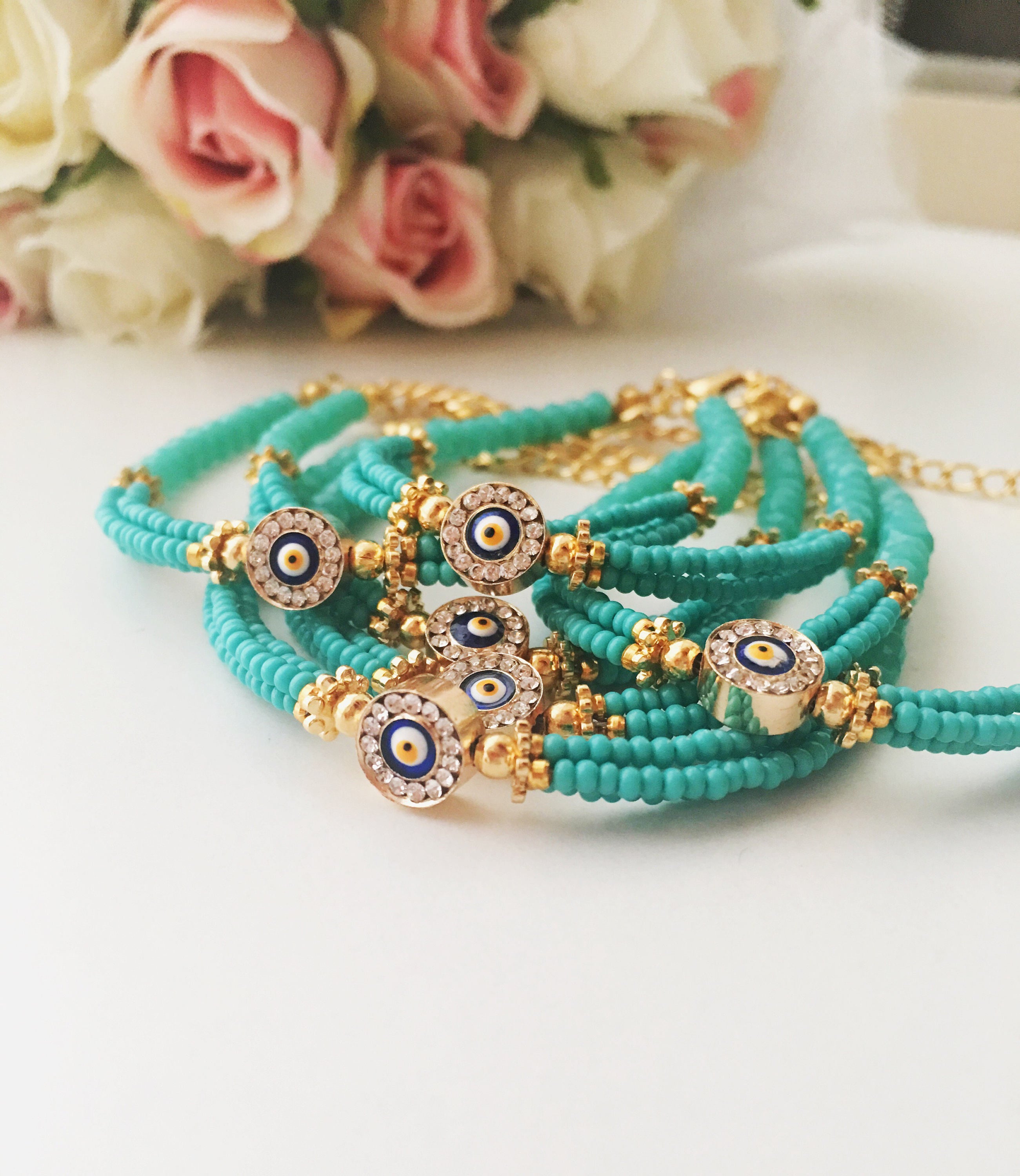 Handmade turquoise seed beads bracelet featuring an evil eye design, showcasing vibrant colors and intricate craftsmanship.