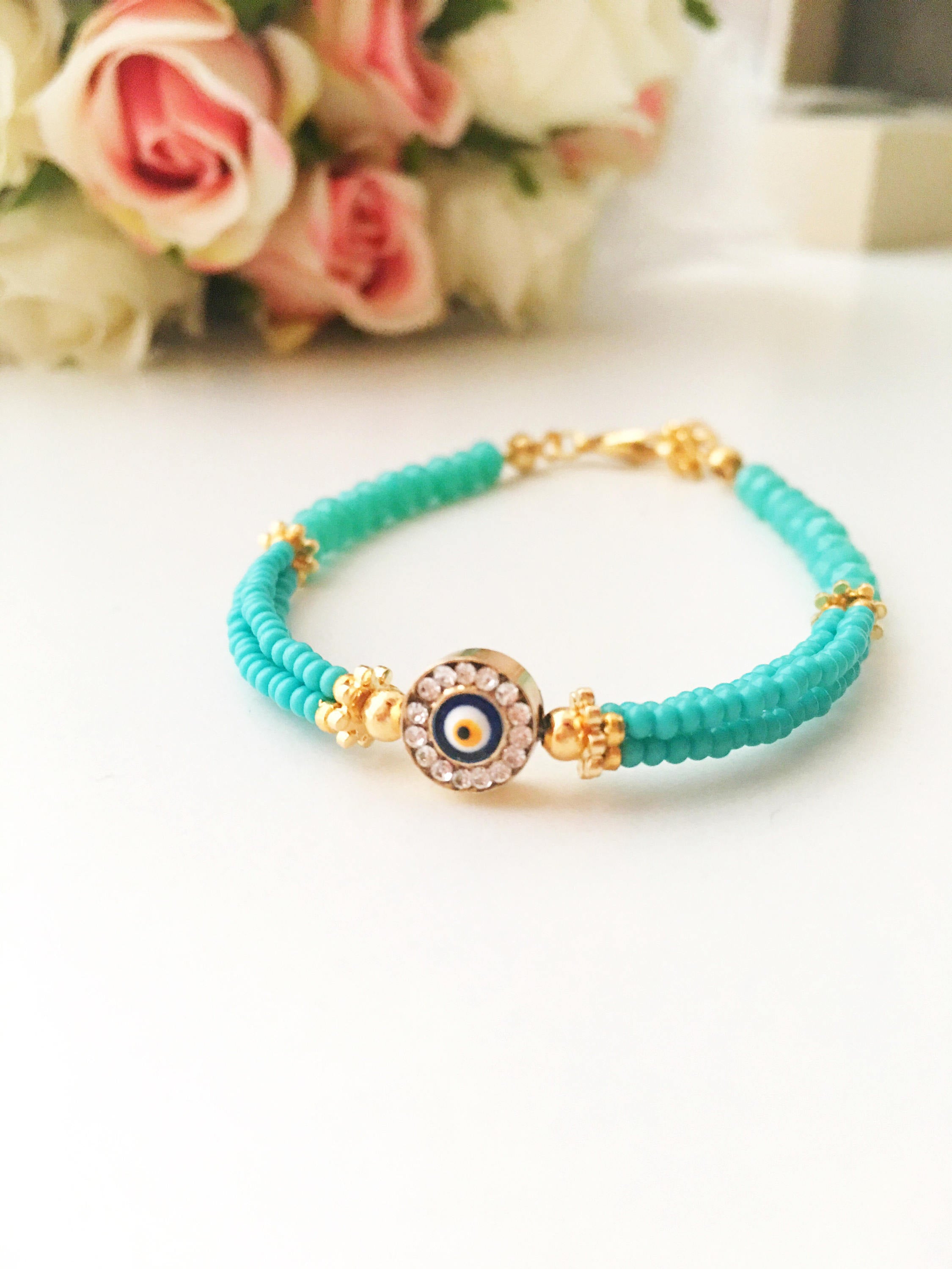 Handmade turquoise seed beads bracelet featuring an evil eye design, showcasing vibrant colors and intricate craftsmanship.