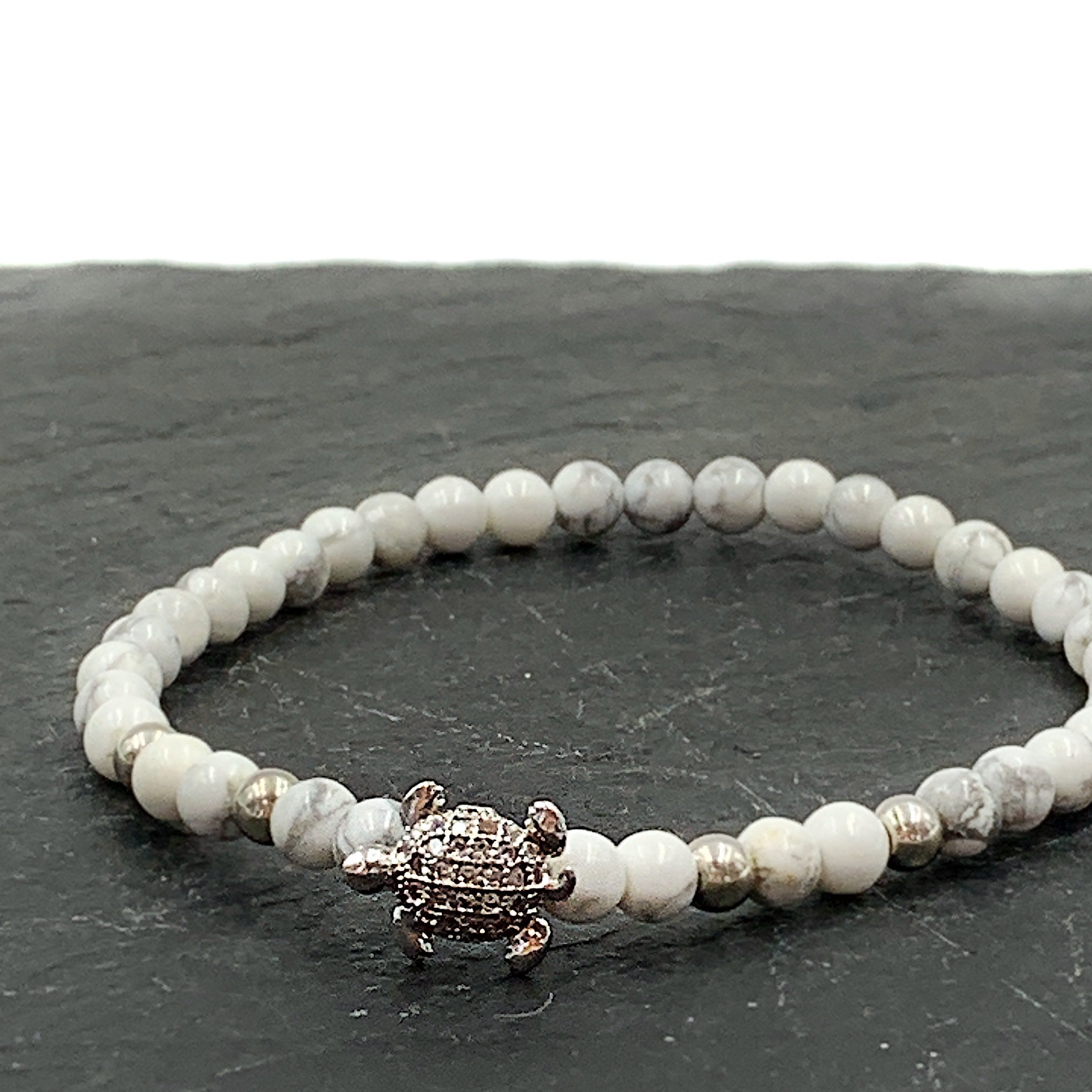 Turtle Stretch Bracelet featuring white howlite beads, silver tone accents, and a sparkling pave crystal turtle charm.