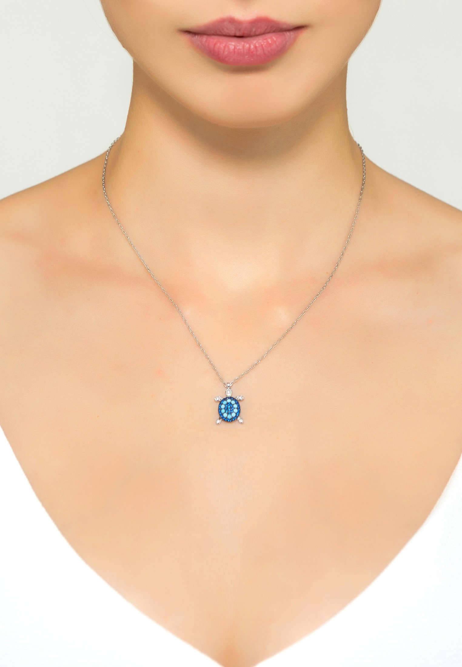 Turtle turquoise blue pendant necklace in silver with cubic zirconia, displayed elegantly on a soft background.