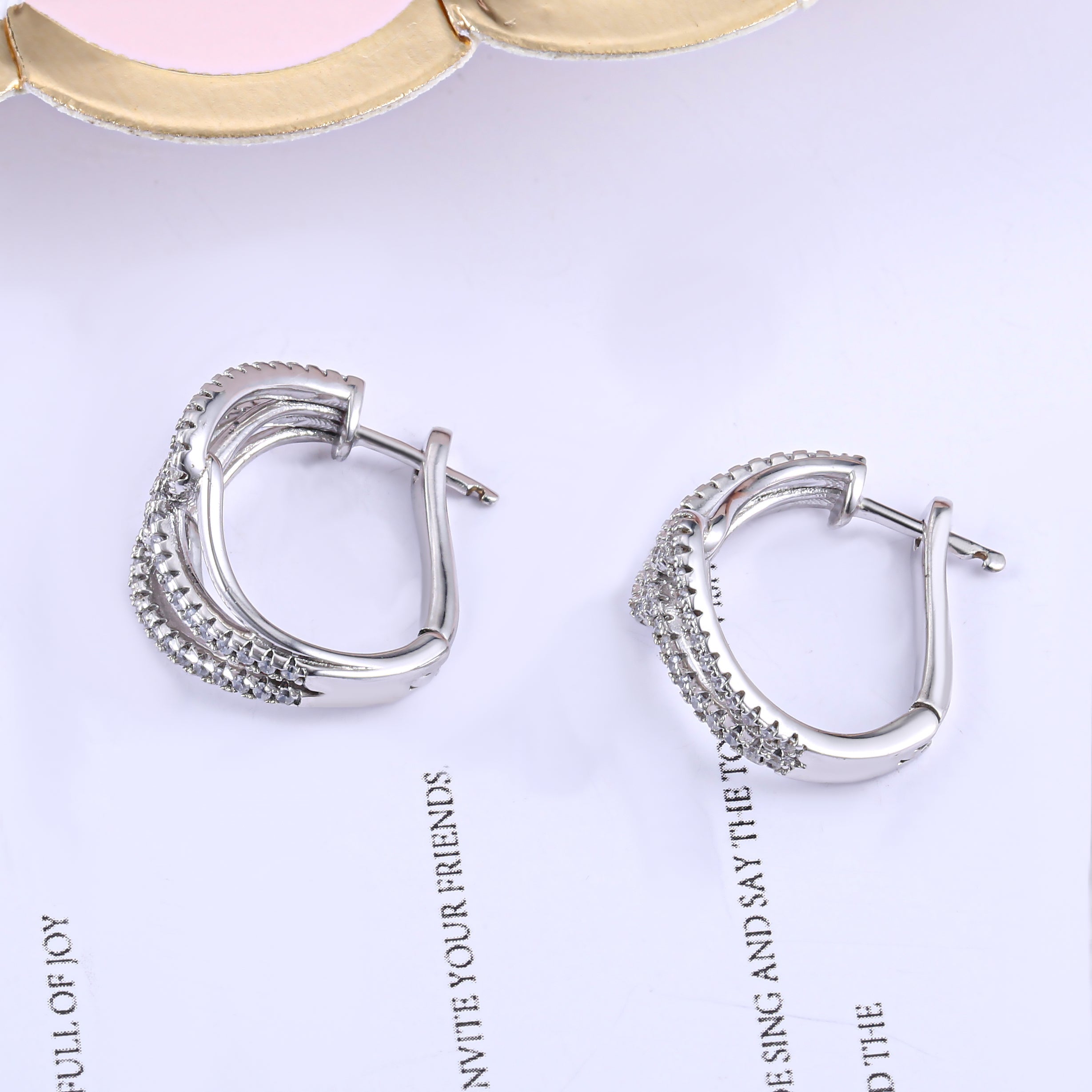 Twist huggie earring made of 925 sterling silver with white sapphire, showcasing a modern design and luxurious finish.