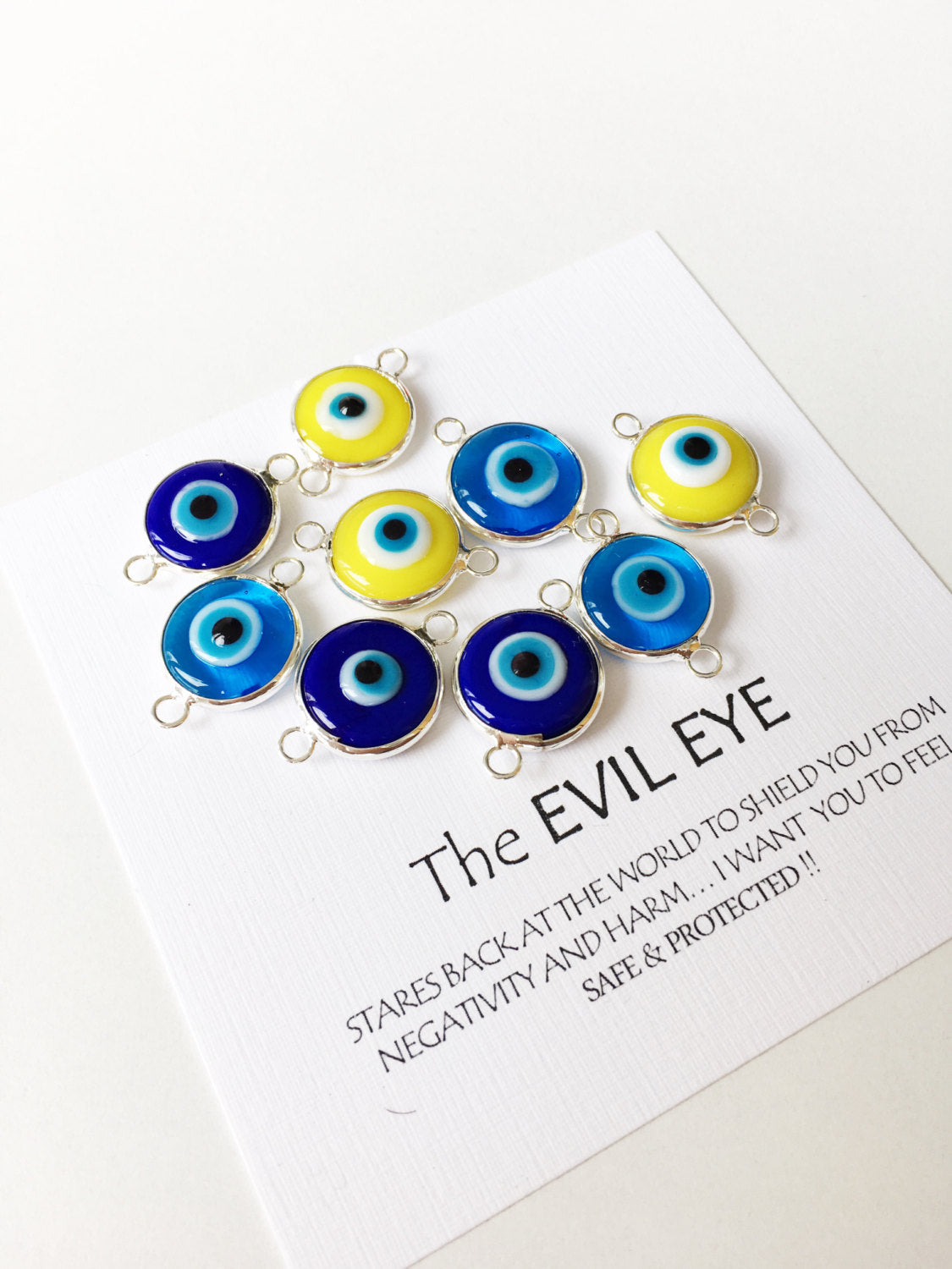 Two connectors glass evil eye charms in blue, yellow, and turquoise colors, featuring silver plating, ideal for jewelry making.