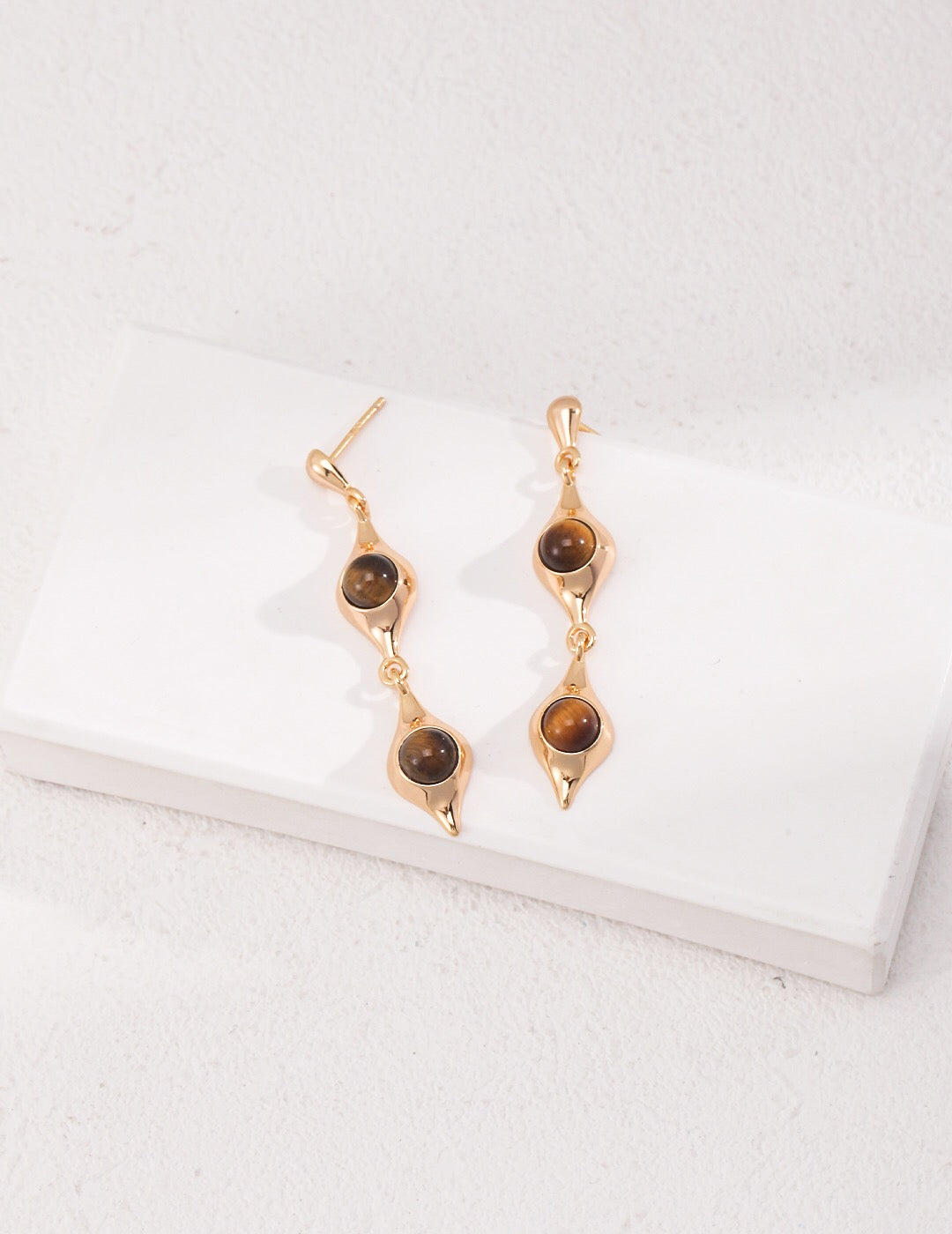 Gold dangling earrings with stones.