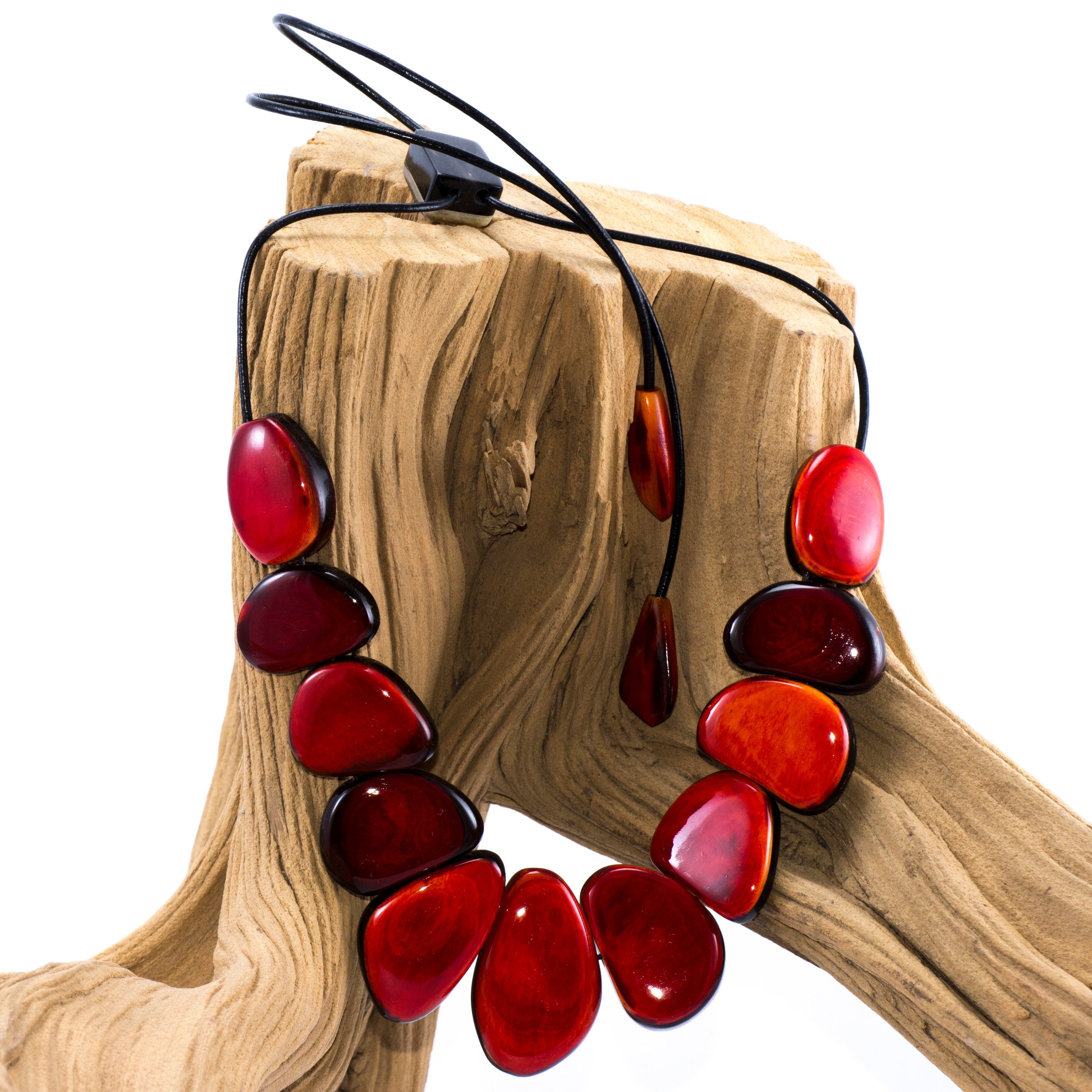 Handmade red buffalo horn necklace with unique pendant and leather cord, showcasing intricate craftsmanship and vibrant color.