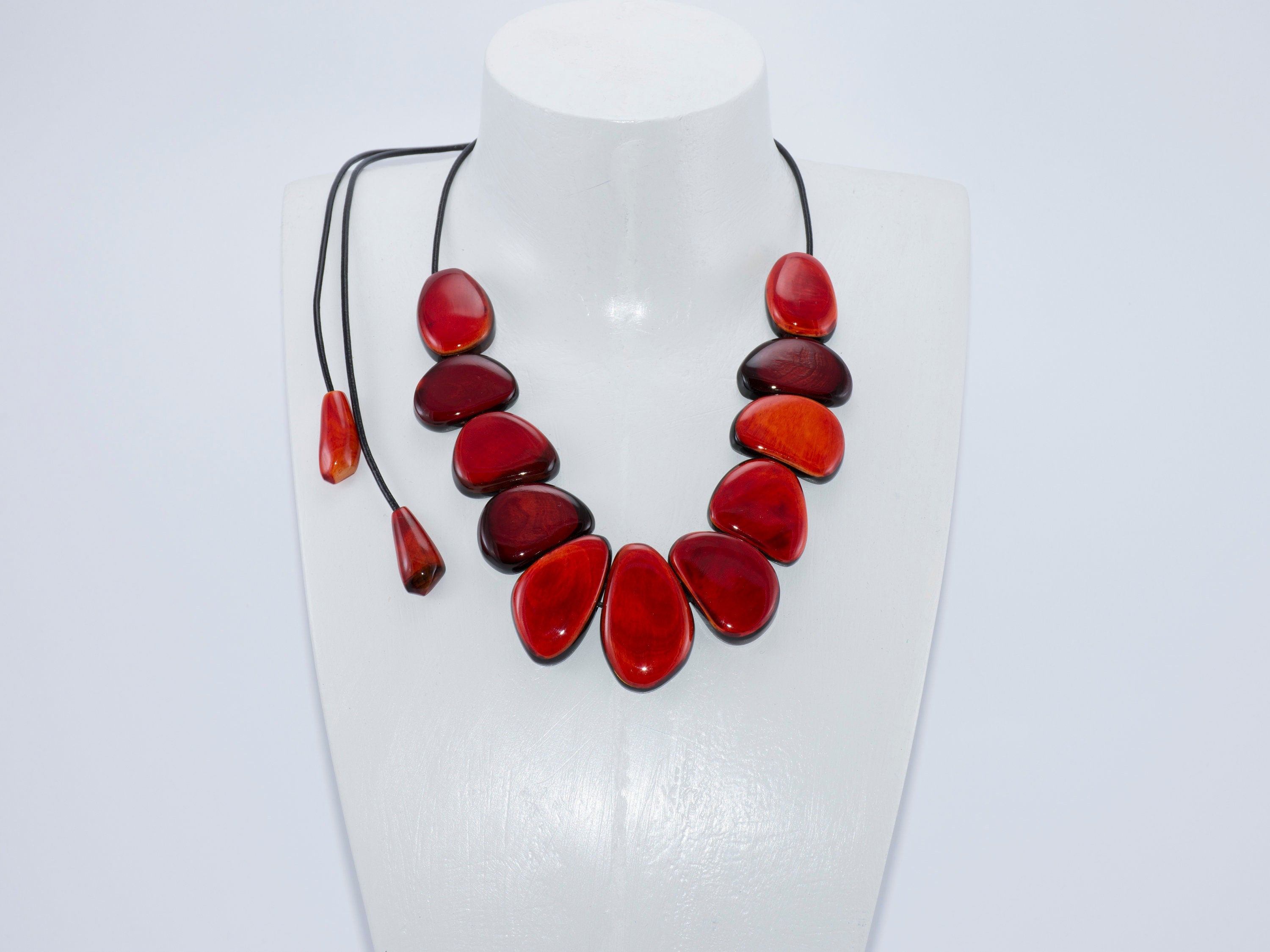 Handmade red buffalo horn necklace with unique pendant and leather cord, showcasing intricate craftsmanship and vibrant color.