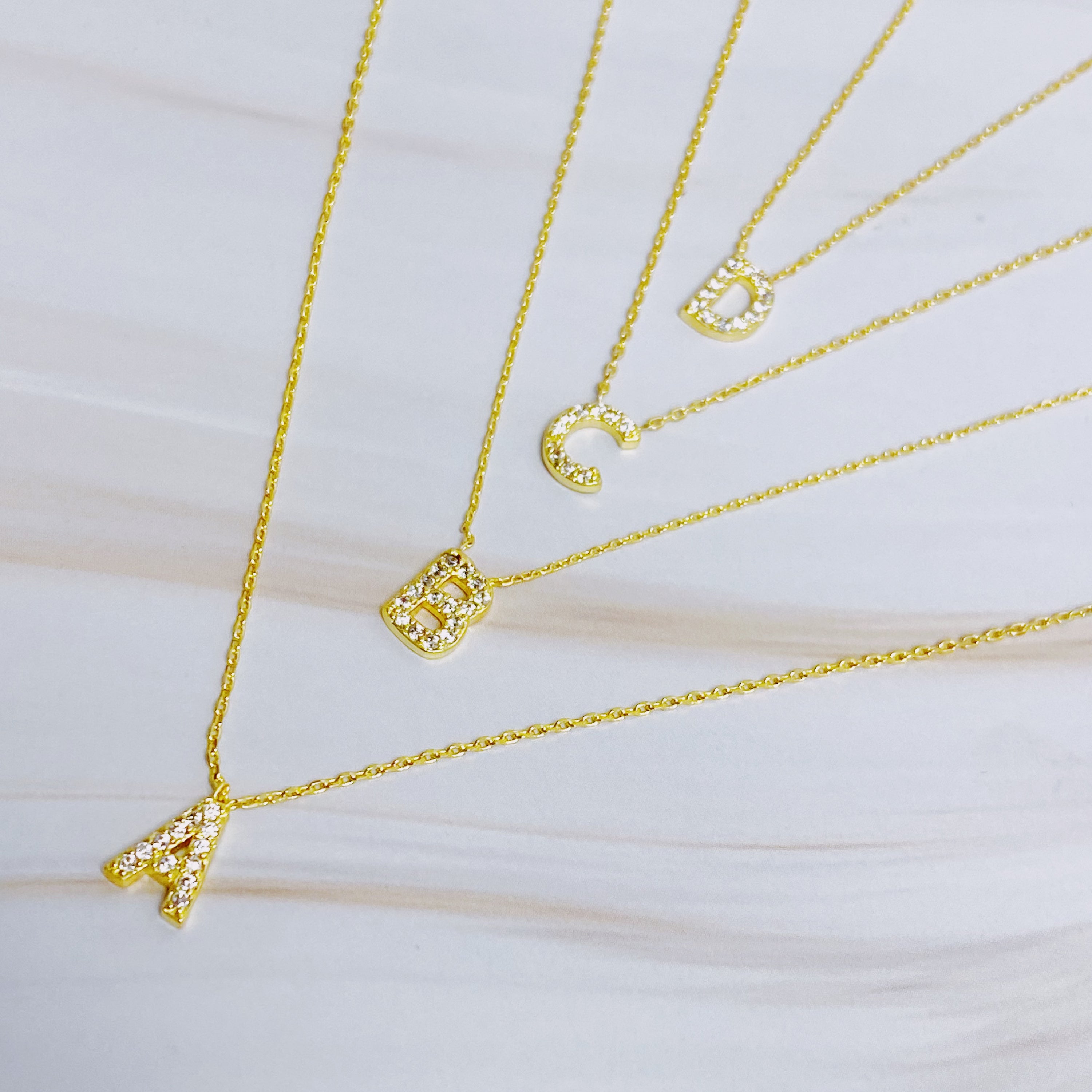 A delicate Understated Beauty Initial Necklace featuring a gold plated initial pendant adorned with sparkling cubic zirconia stones.